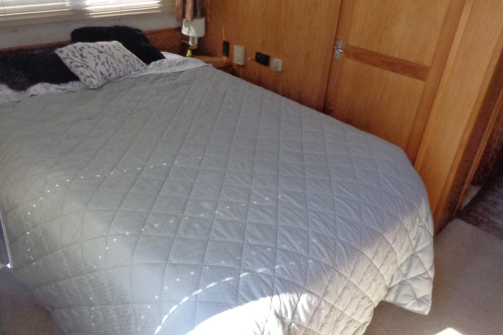 Cozy bedroom interior of 1992 Cruise-A-Home Corsair 4200 with quilted bedspread.
