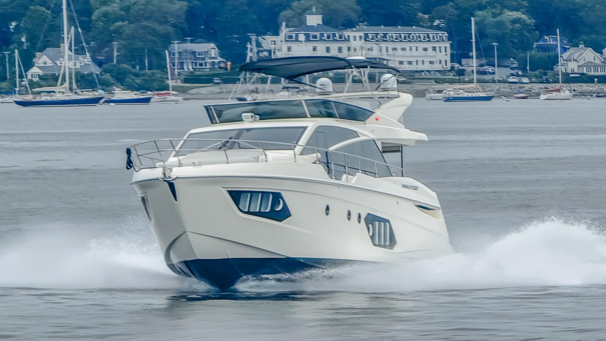 2019 Absolute 50 Fly yacht cruising on water with scenic coastal background.