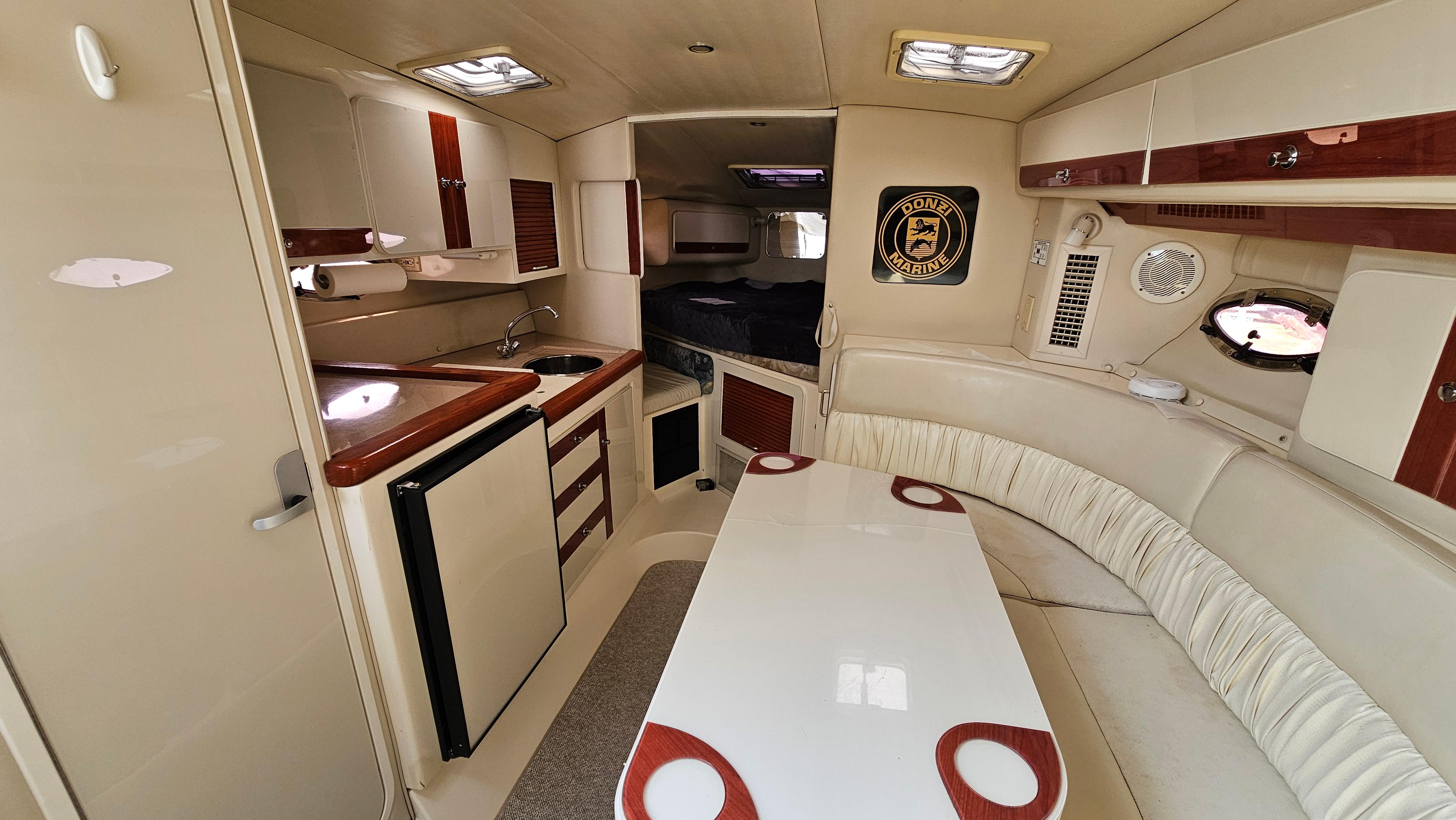 1997 Donzi 3250 LXC cabin interior with kitchenette, seating, and dining area.