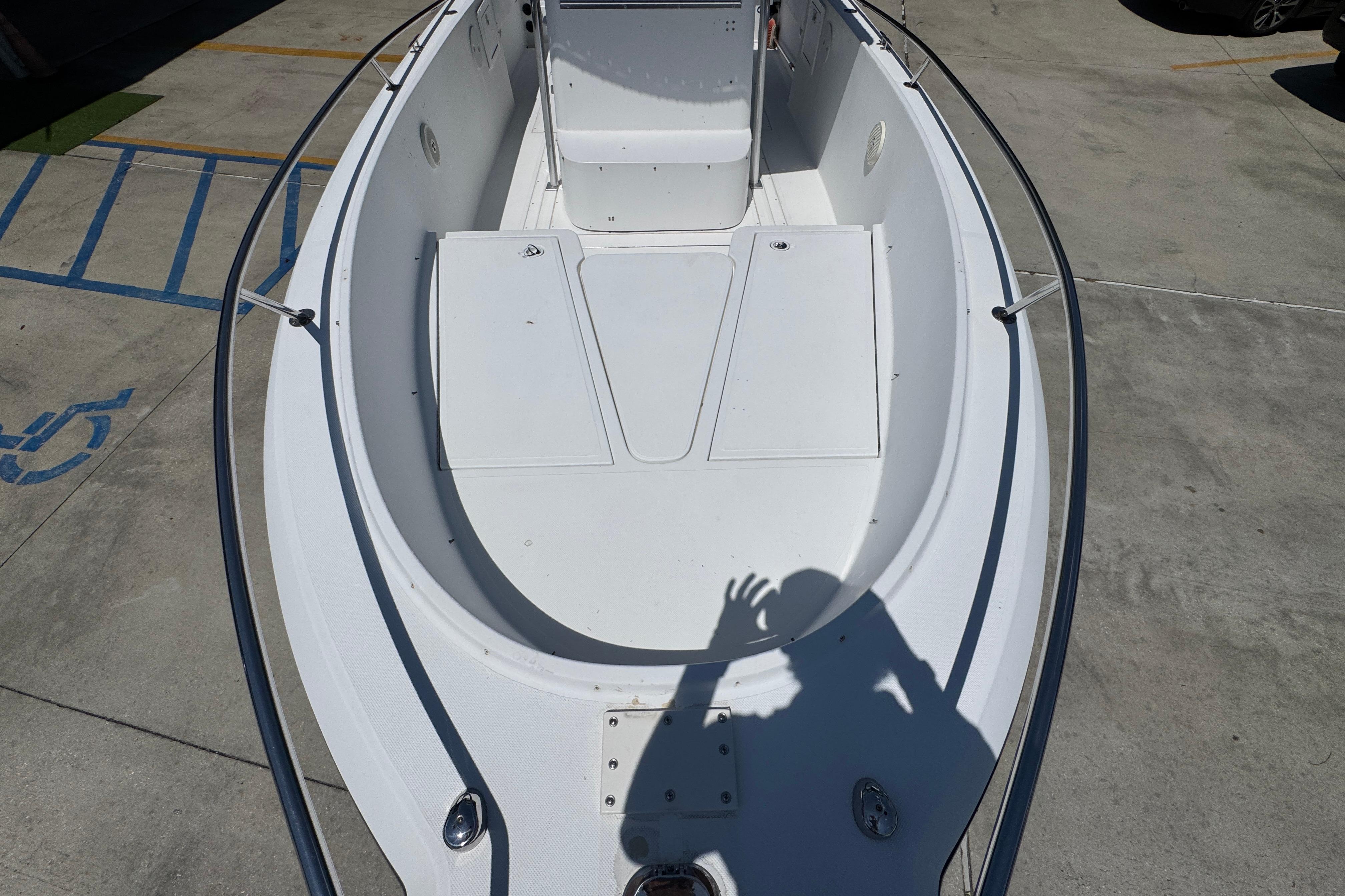 2000 Stamas 250 Tarpon boat deck, white interior, shadow visible, parked on concrete.
