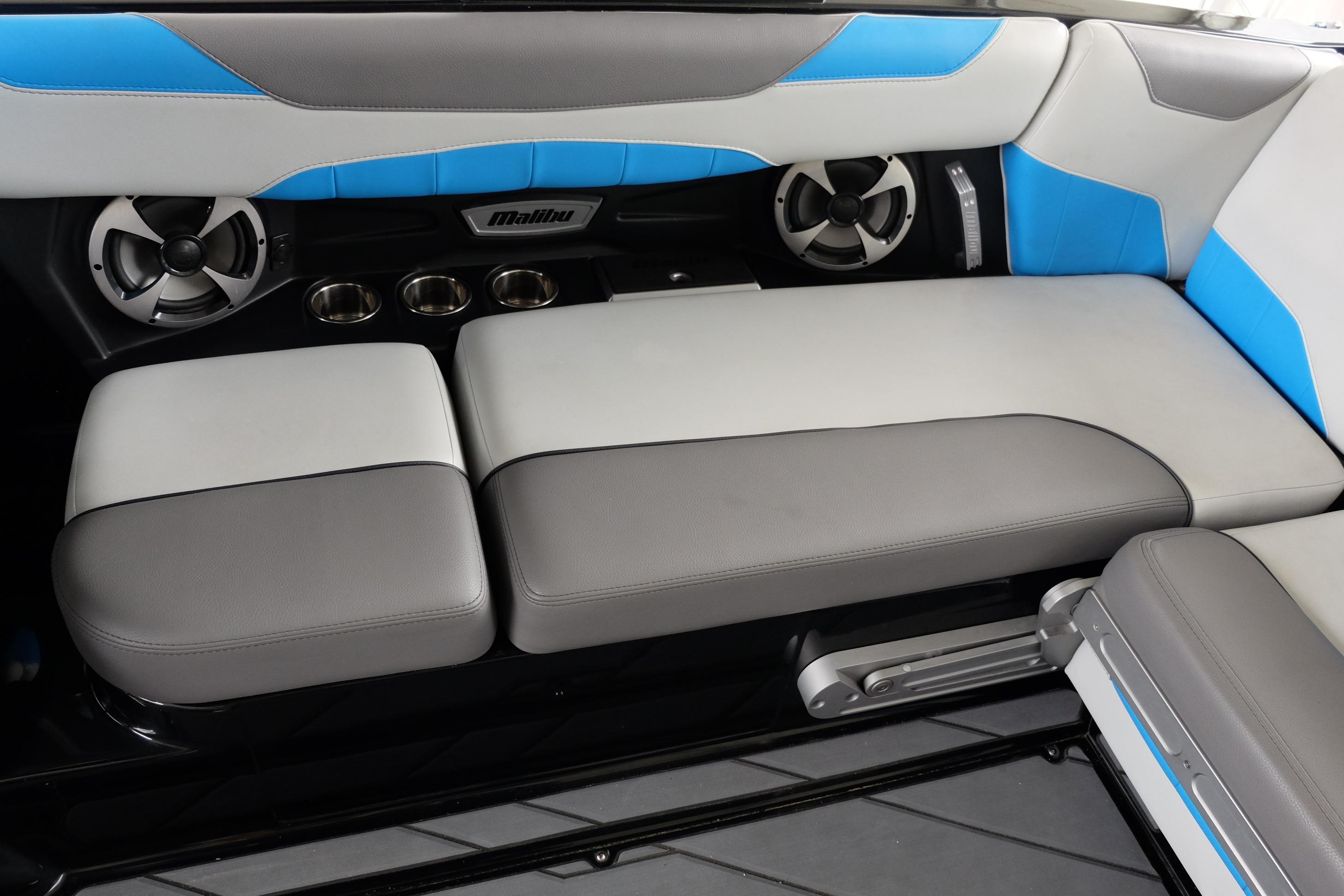 2020 Malibu Wakesetter 23 LSV interior seating with blue and gray upholstery, featuring cup holders and speakers.