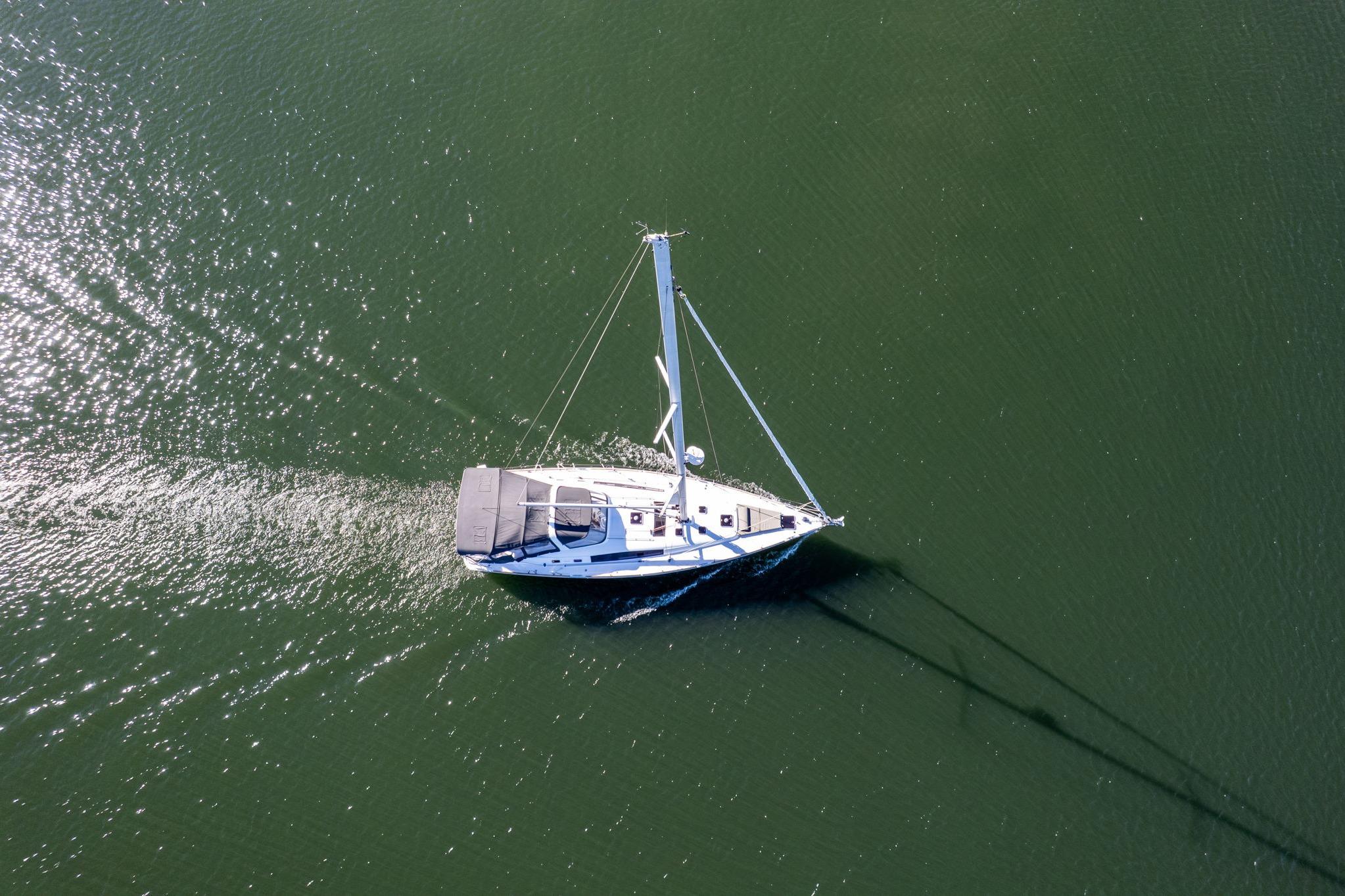 Aerial view of 2013 Beneteau Oceanis 50 sailing on calm green waters.