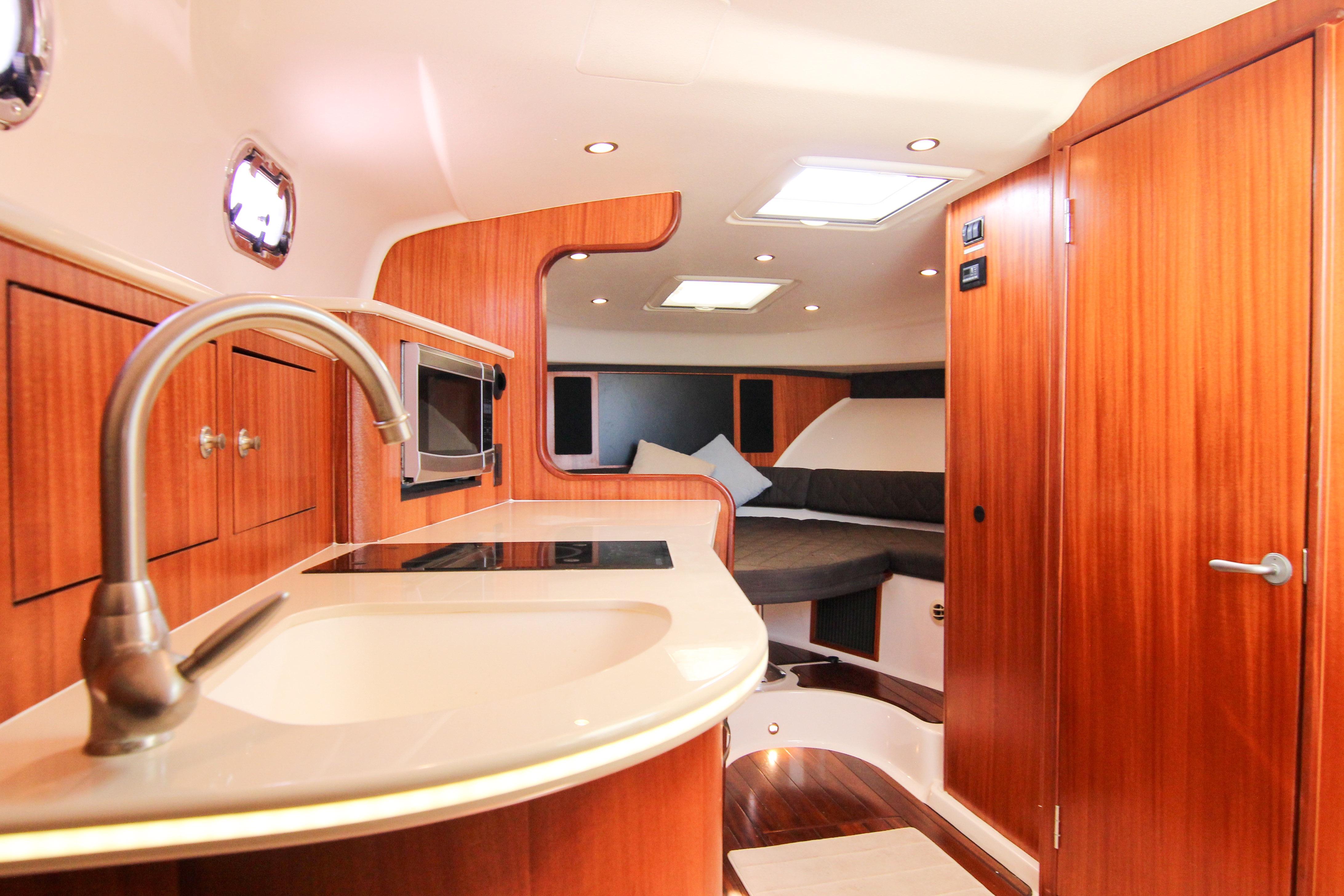 Luxurious interior of 2016 Pursuit OS 385 Offshore boat with modern kitchen and cozy seating.
