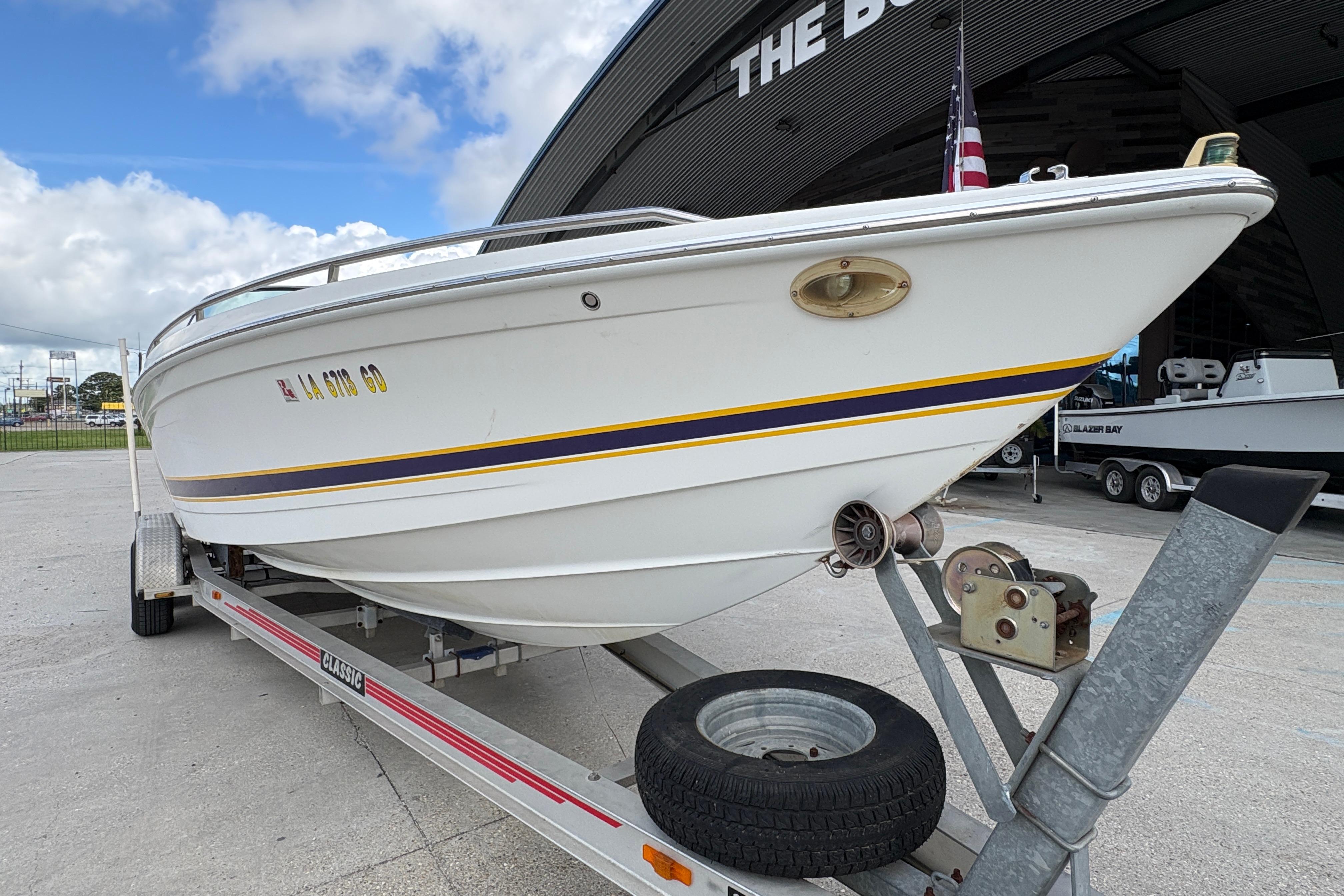 2002 Formula 292 FASTech boat on trailer, parked outside a building under a cloudy sky.