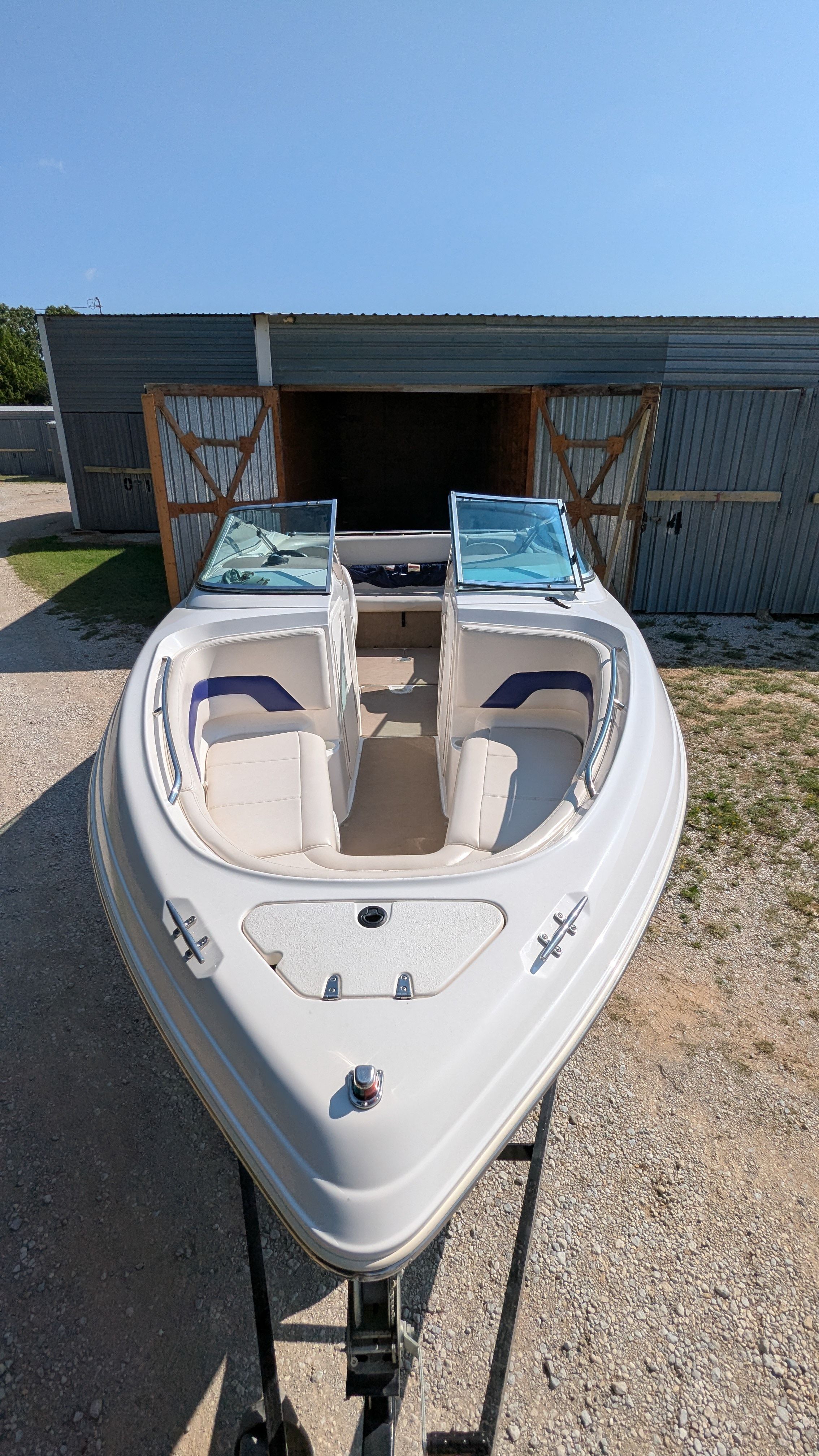 A 2000 Chaparral 240 SSi boat on a trailer in front of a garage.