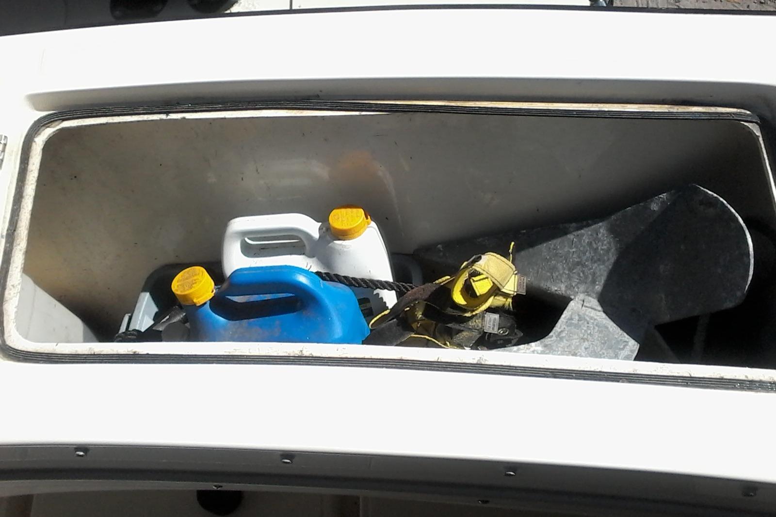 Storage compartment of 2002 Albemarle 265 Express Fisherman with containers and anchor.
