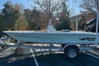 2026 Mako 18 Pro Skiff boat on trailer, parked outdoors with trees in background.
