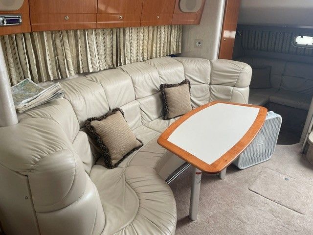 Interior of a 2002 Formula PC 37 with beige leather sofa and wooden table.