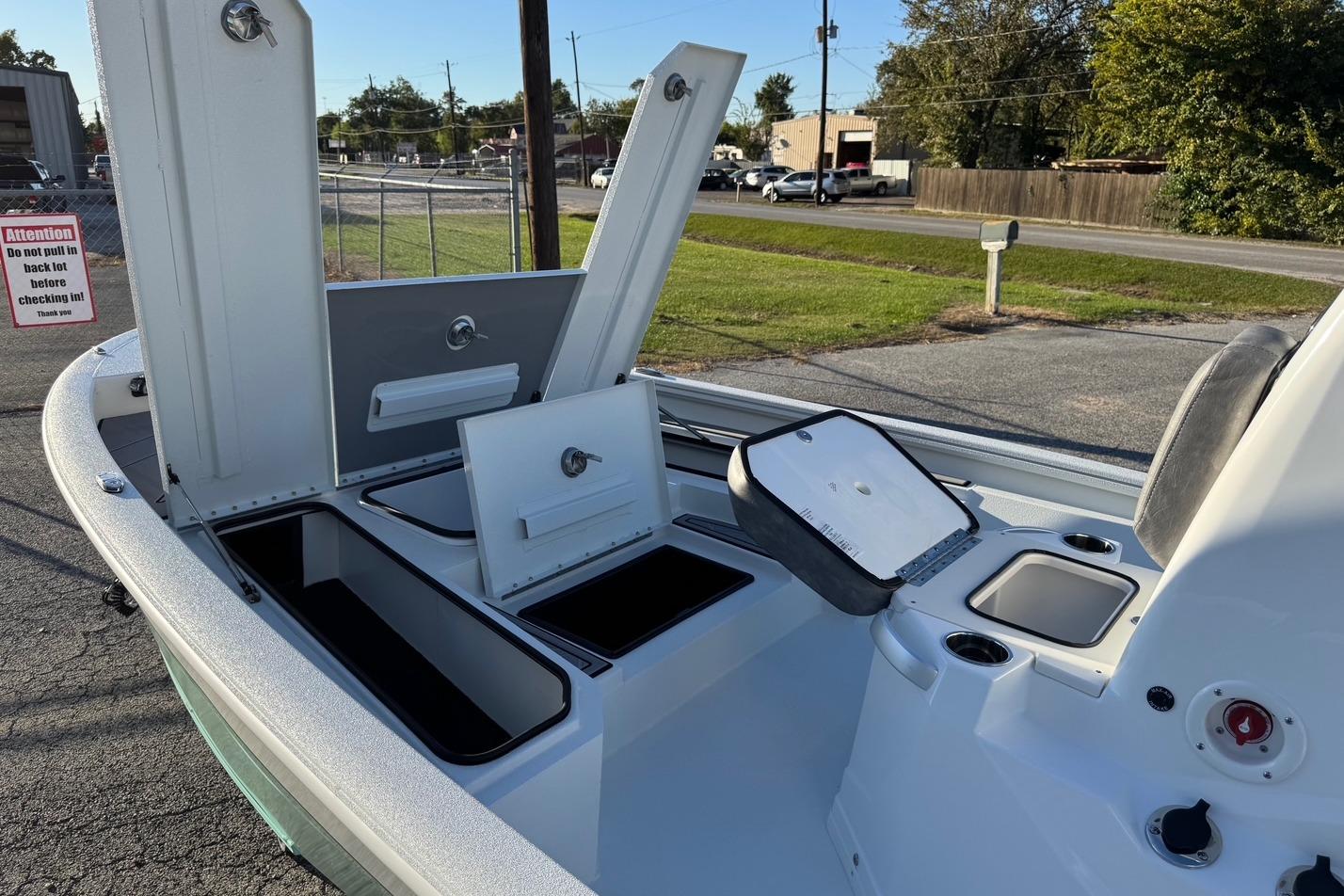2025 Avid 23 Mag boat interior with open storage compartments and control panel.