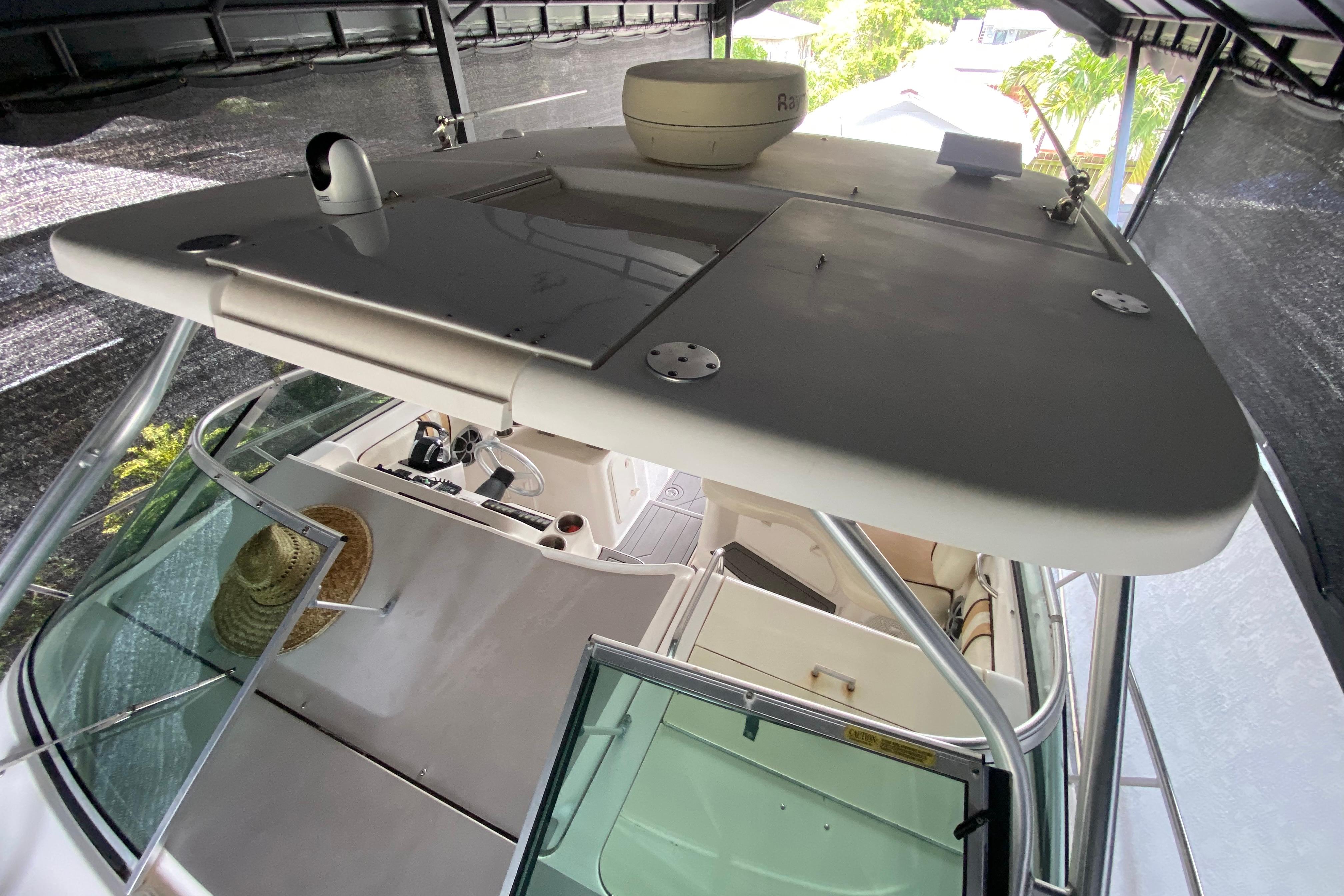 2005 Wellcraft 290 Coastal boat interior, featuring helm and seating under a covered dock.