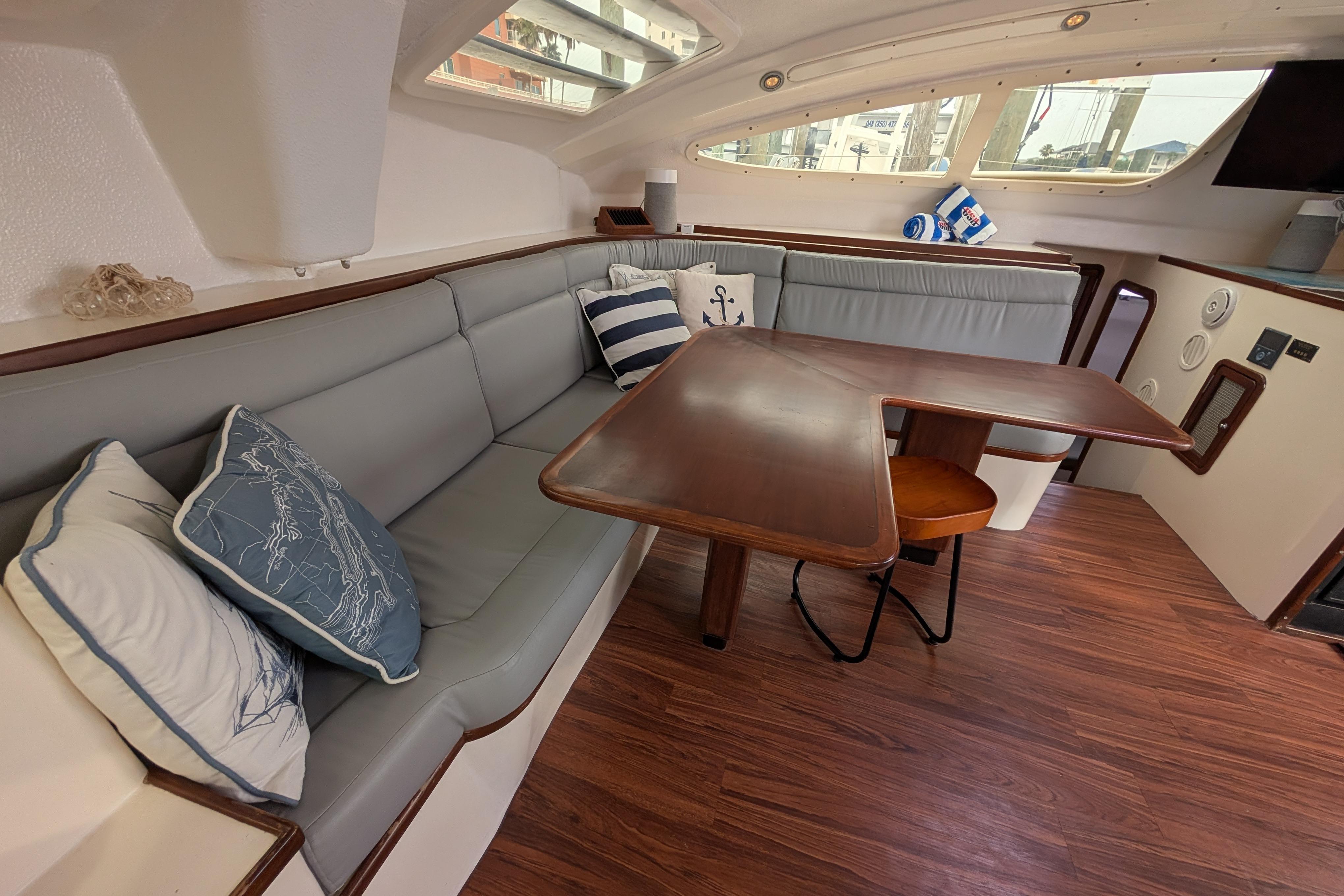 Cozy interior of 1999 Island Spirit 37 yacht with cushioned seating and wooden table.