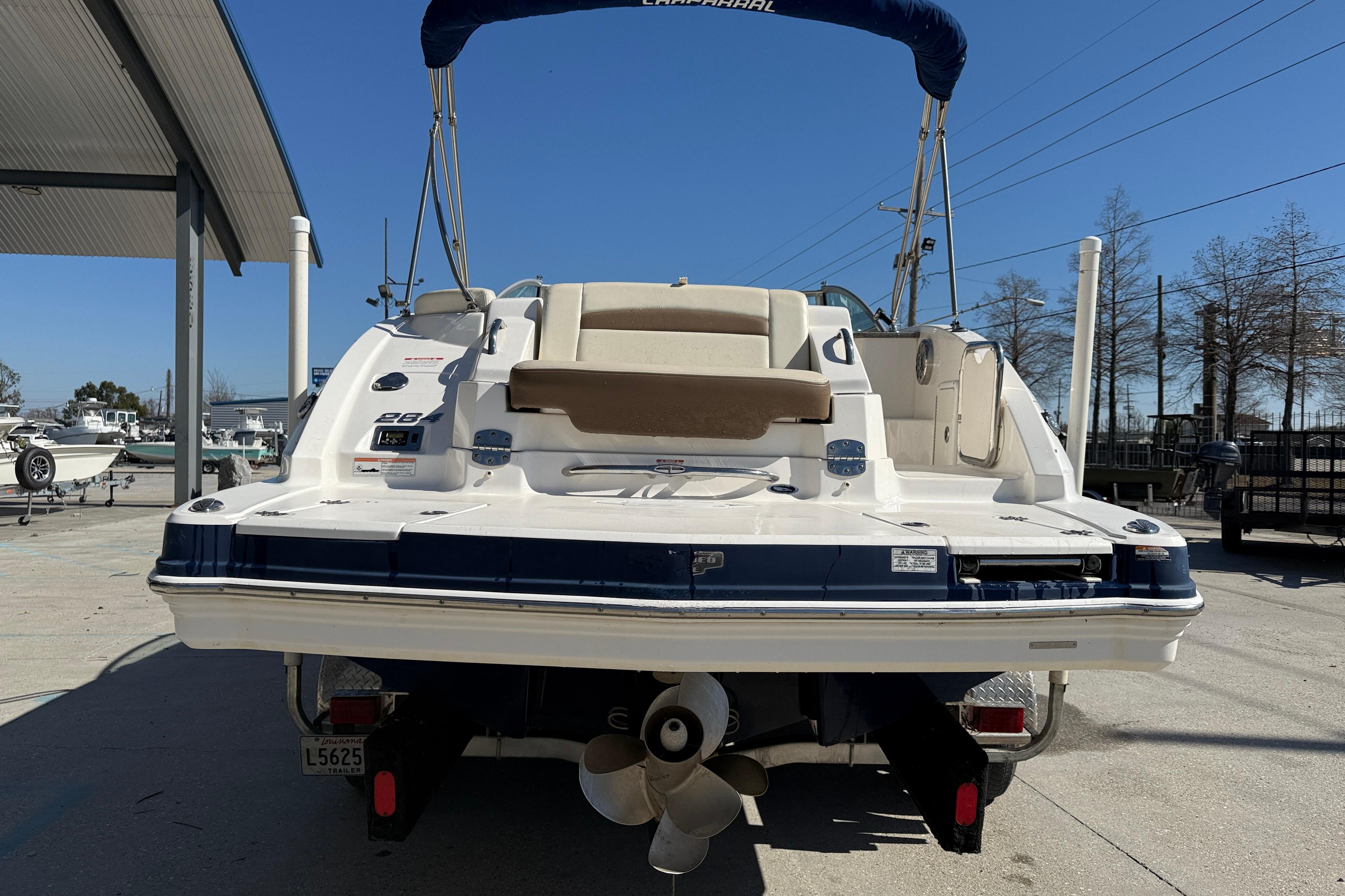 2014 Chaparral 264 Sunesta boat rear view, parked outdoors under clear blue sky.