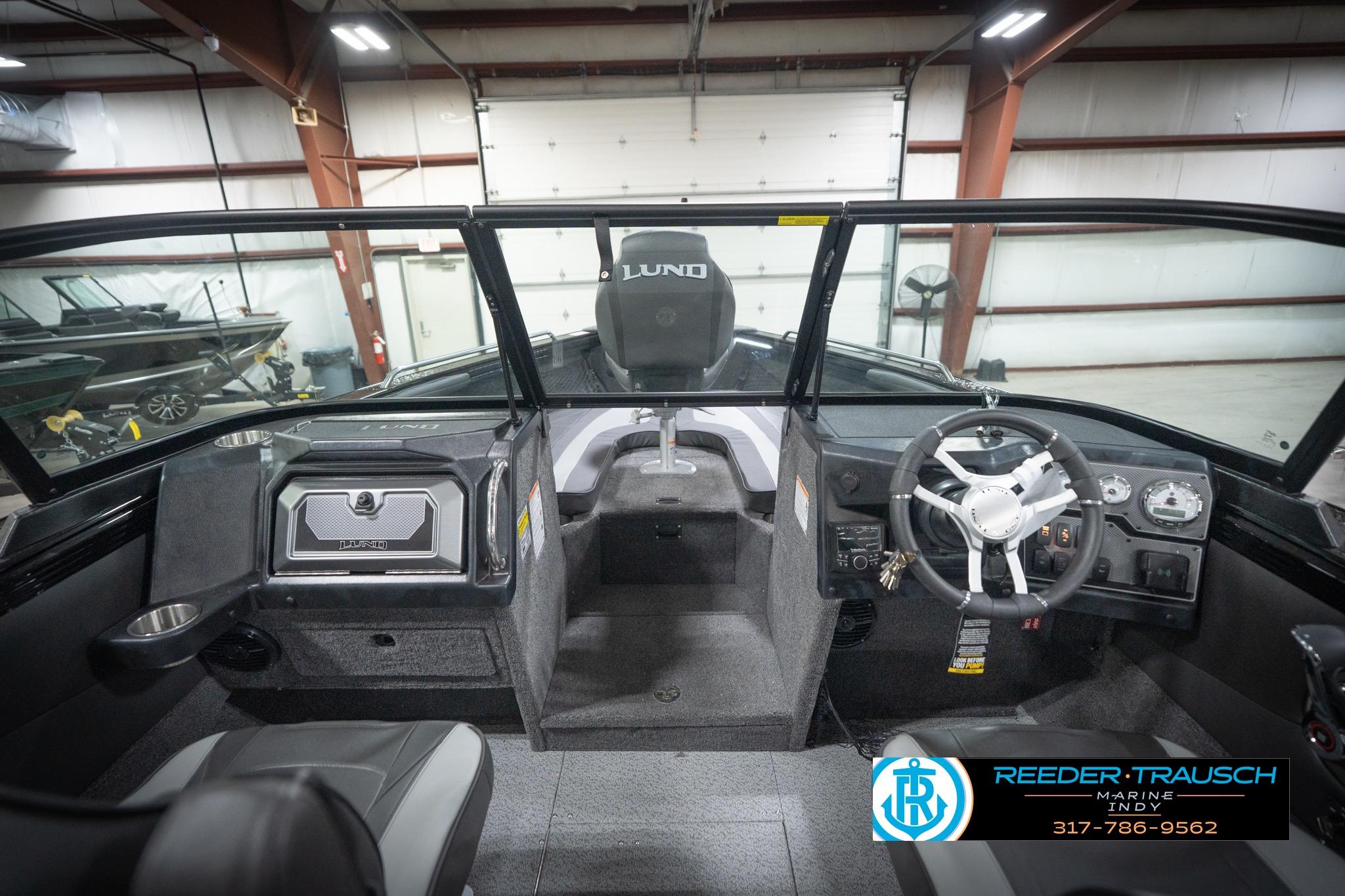 2026 Lund 2275 Baron boat interior with steering wheel and dashboard in a showroom.