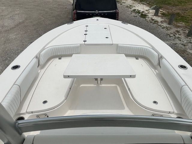 The image shows the bow of a 2015 Robalo 246 Cayman with white cushioned seating and a table.