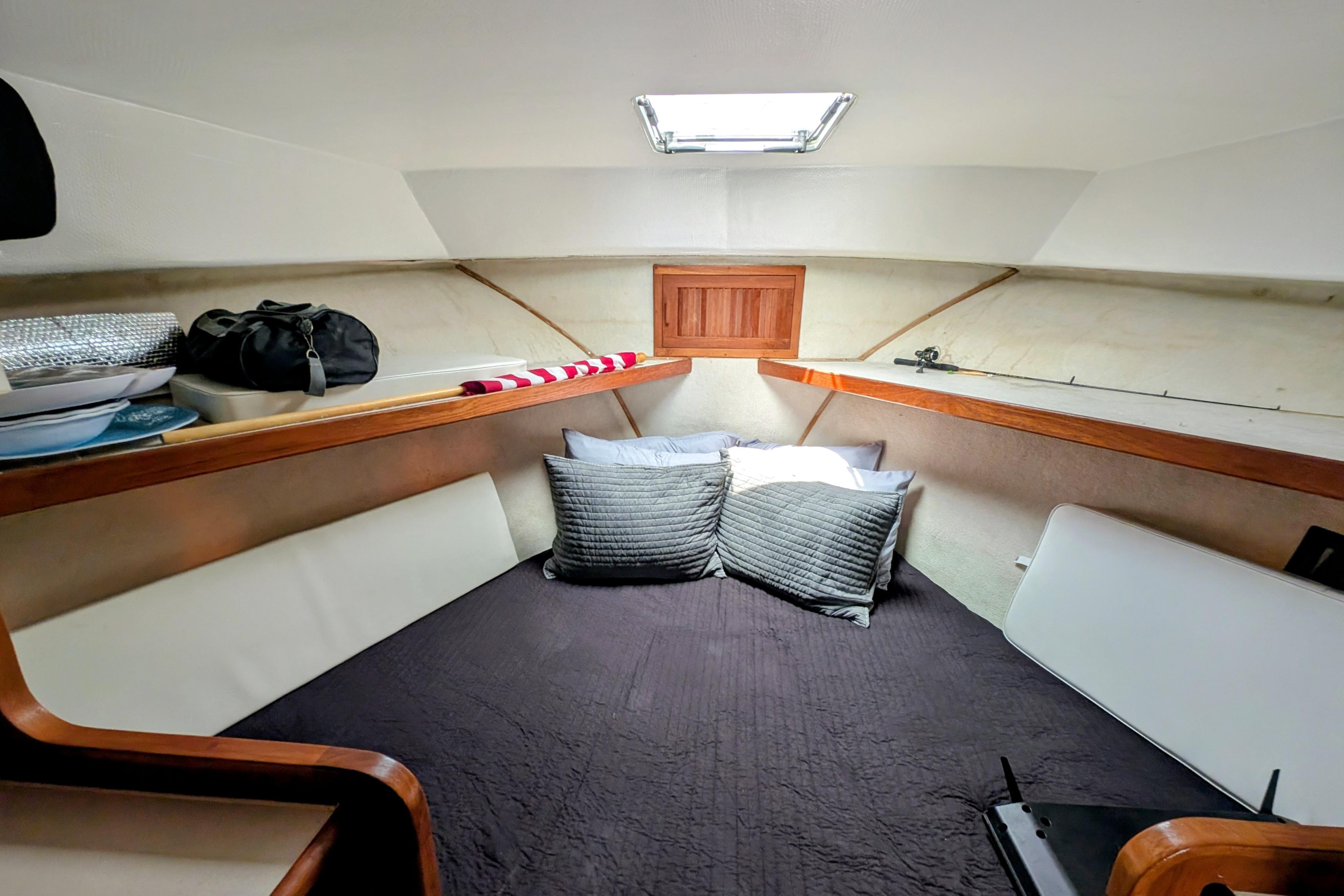 Cozy cabin interior of 1998 Markley 46 boat with pillows and storage shelves.