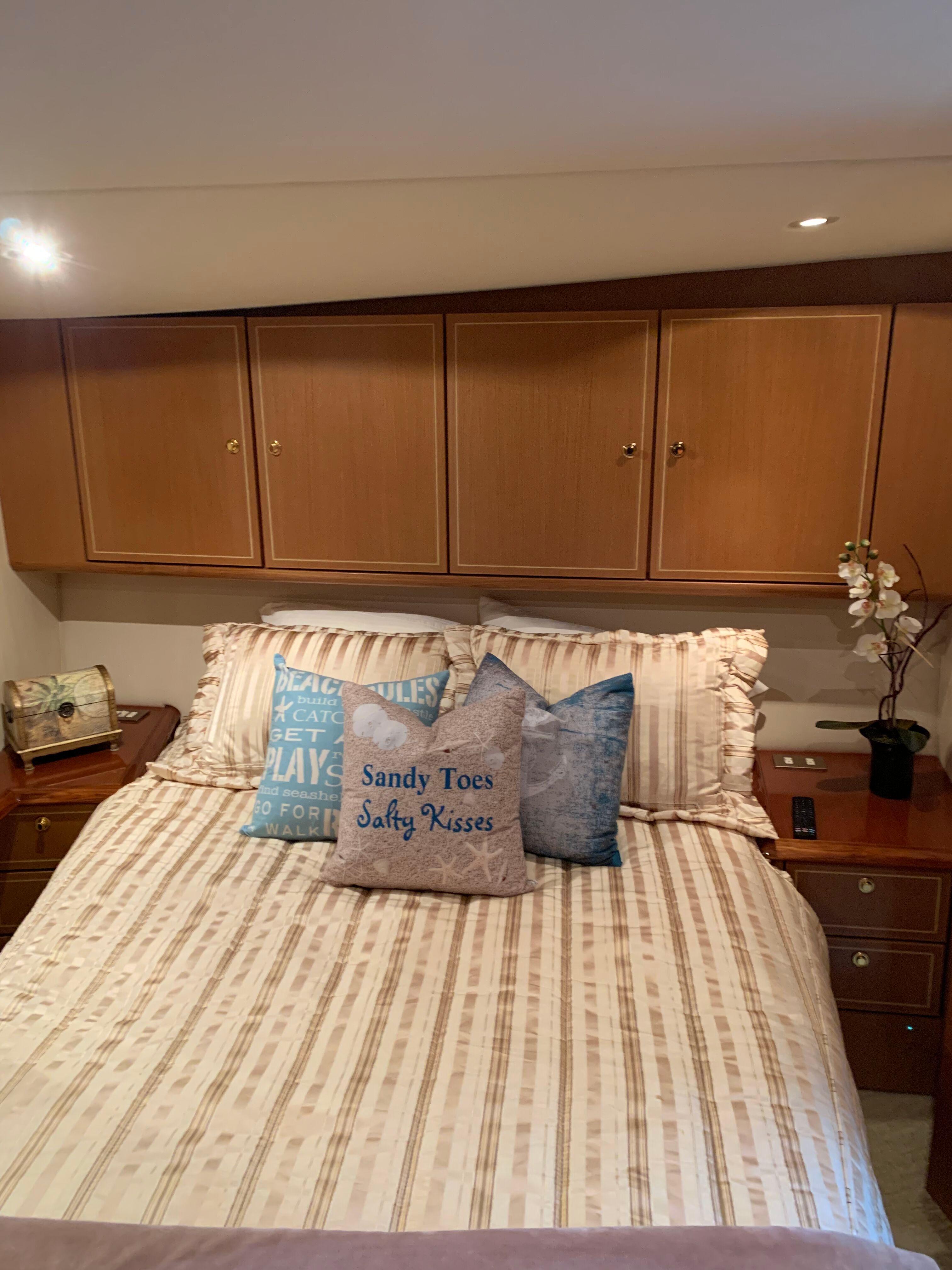 Cozy bedroom in 2004 Ocean Yachts 57 Odyssey with nautical-themed pillows and wooden cabinets.