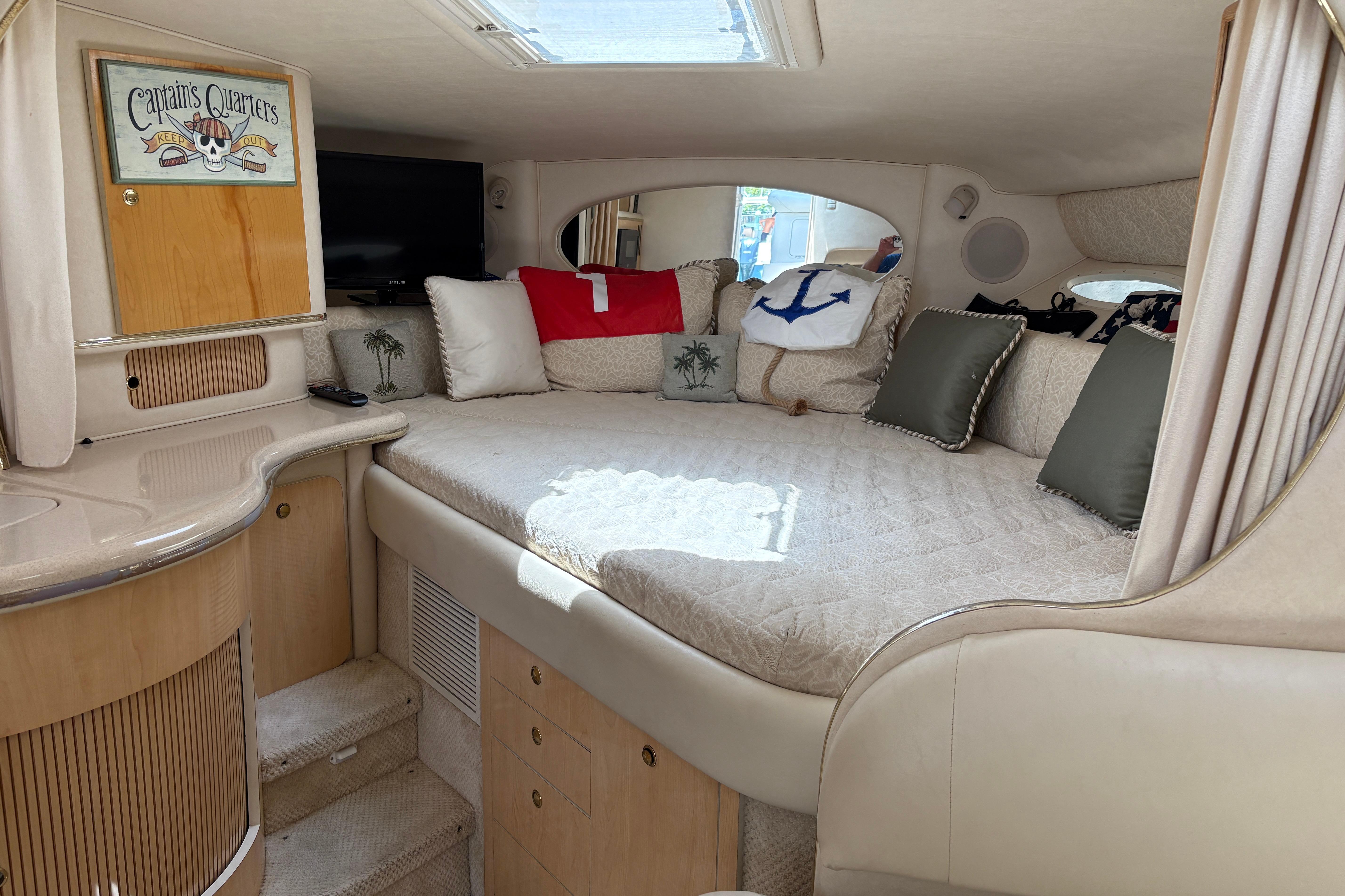 Interior of 2001 Sea Ray Sundancer 310 with cozy bed and nautical decor.