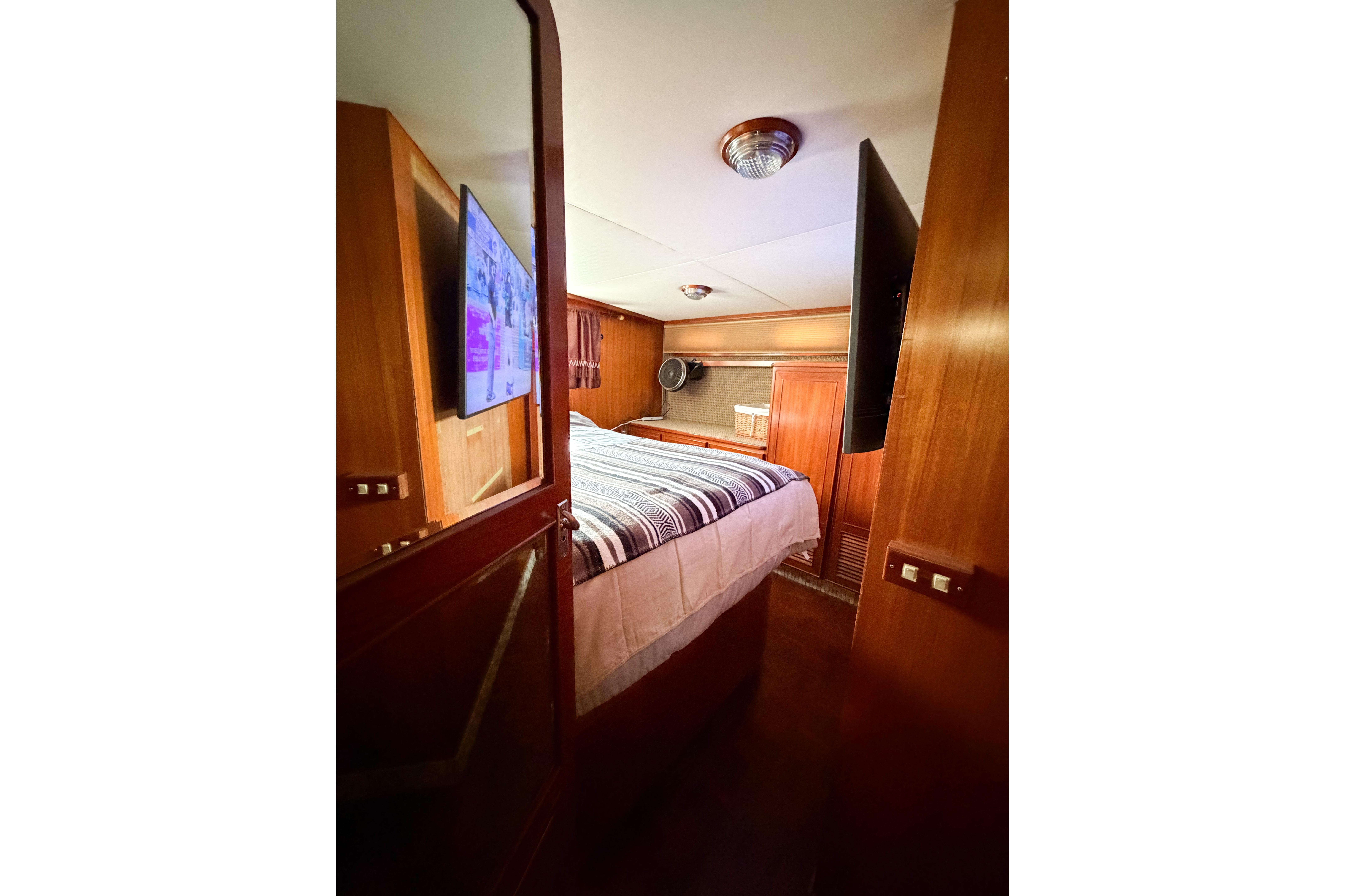 Cozy bedroom in 1989 Jefferson Marquessa 52 yacht with wood paneling and TV.