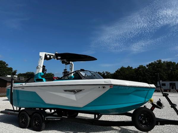 2022 Nautique S23 boat on trailer, vibrant blue and white design, parked outdoors.