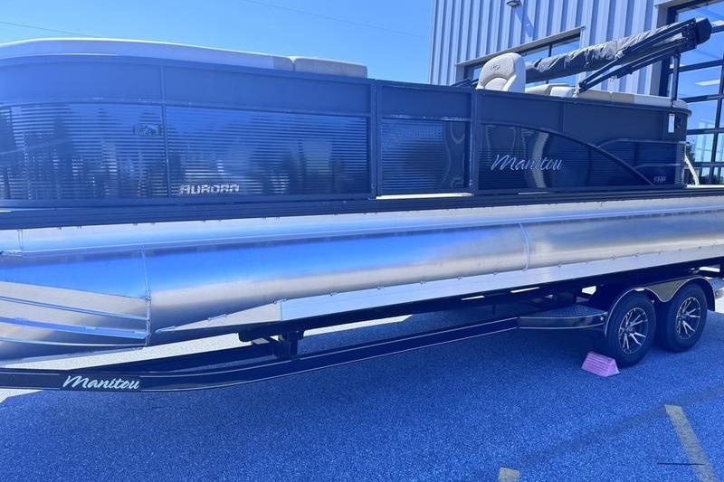2027 Manitou Aurora 23 RF SHP pontoon boat on trailer, parked outdoors.