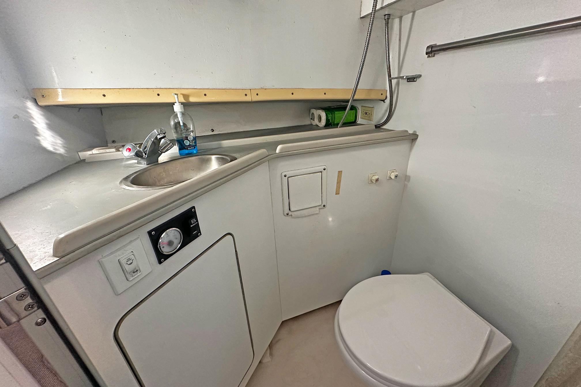 Compact bathroom in a 1990 Boston Whaler 36 Defiance boat, featuring sink and toilet.