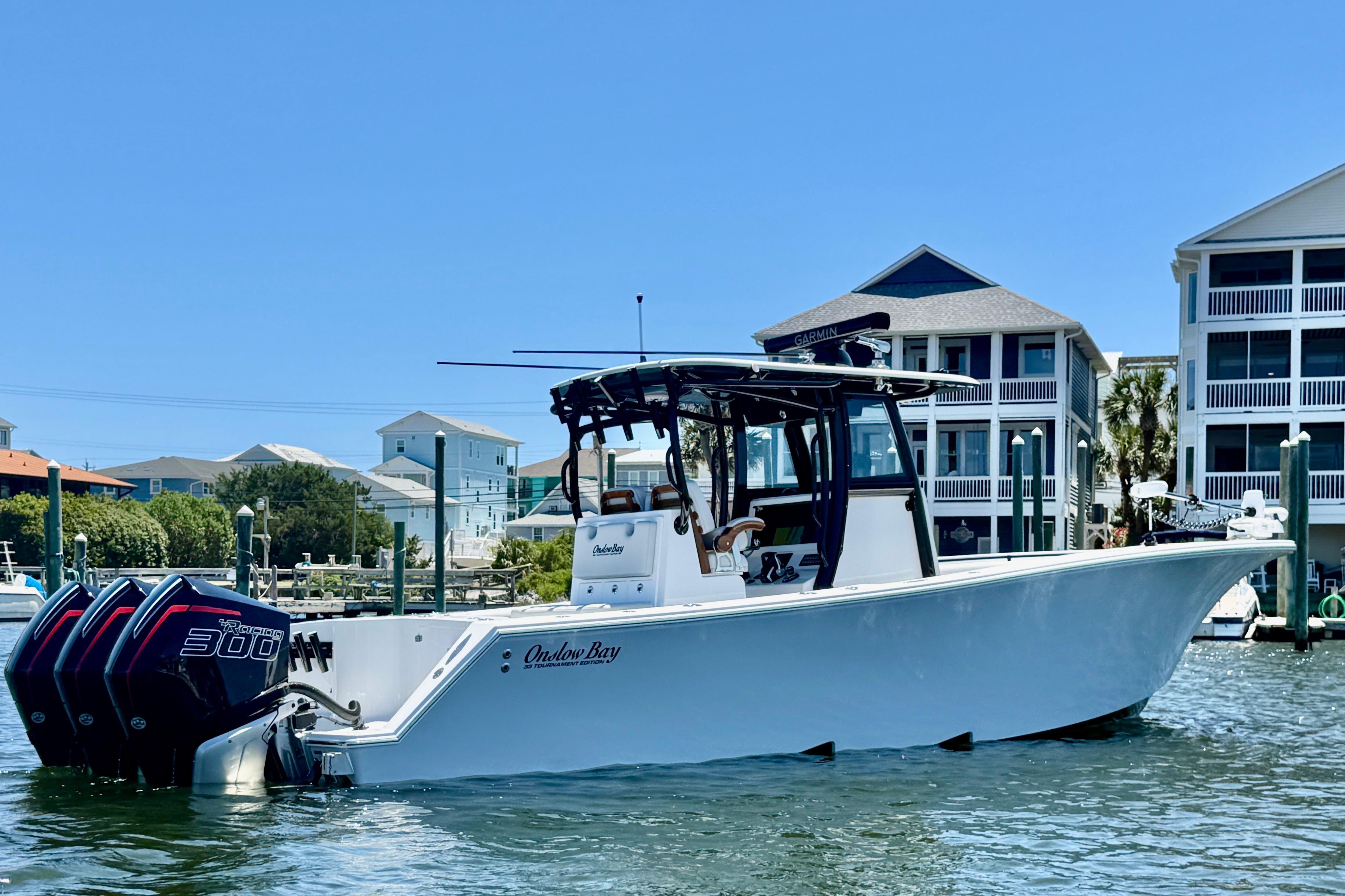2026 Onslow Bay boat with triple 300 horsepower engines docked near waterfront homes.