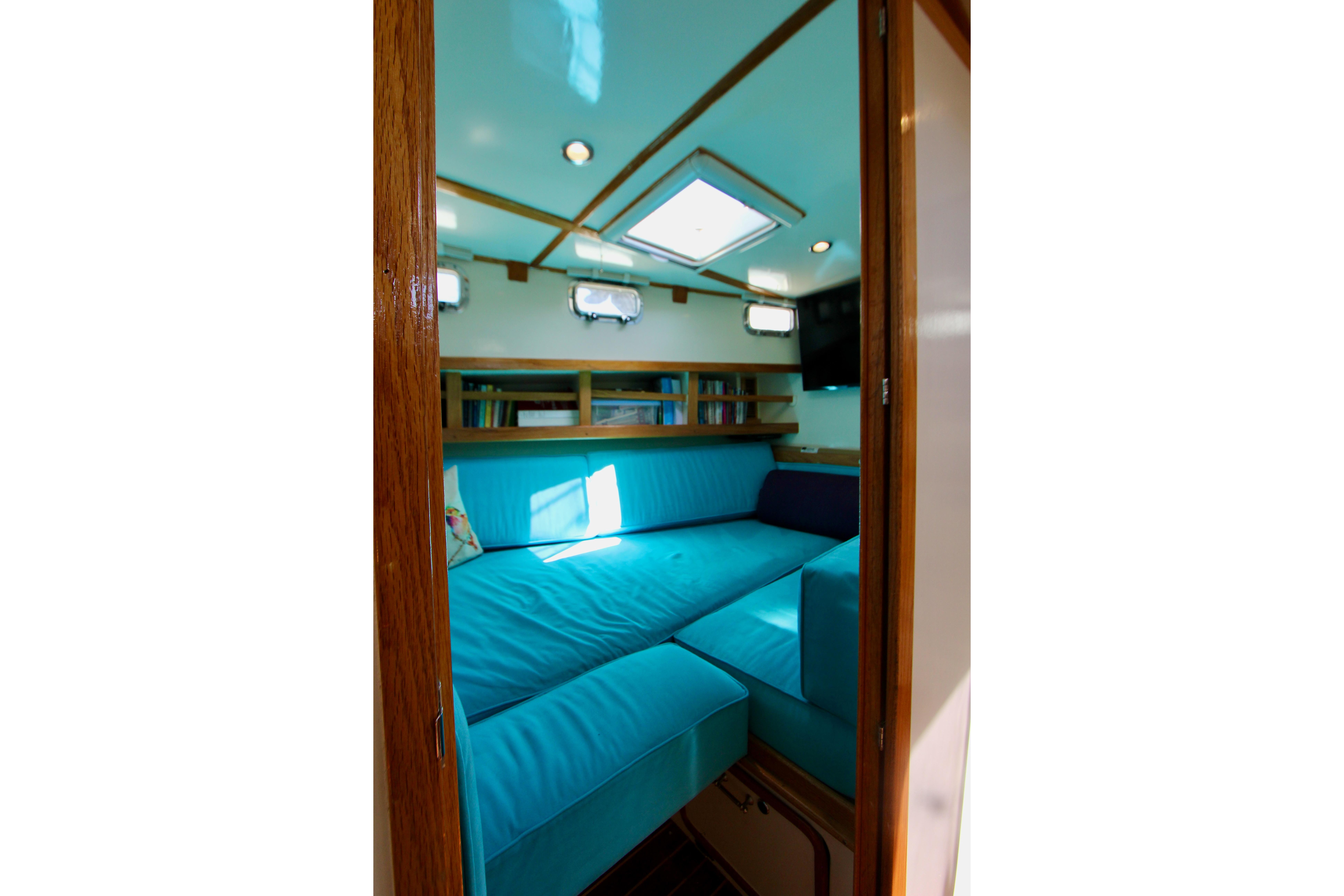 Interior of 1995 Benford Custom Pilothouse Cutter with blue seating and wooden accents.