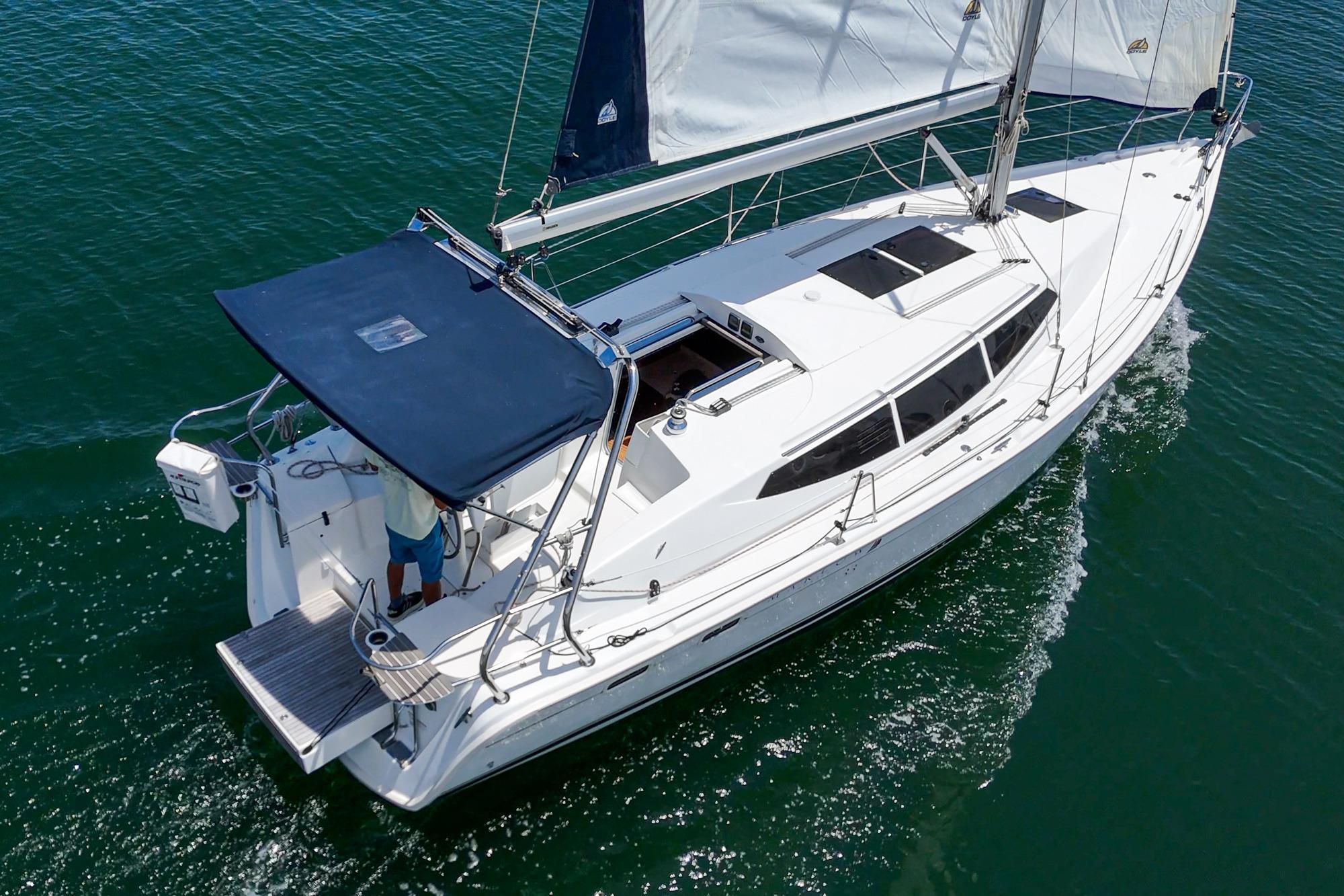 Sailing on water, 2015 Hunter 33 yacht with white sails and blue canopy.