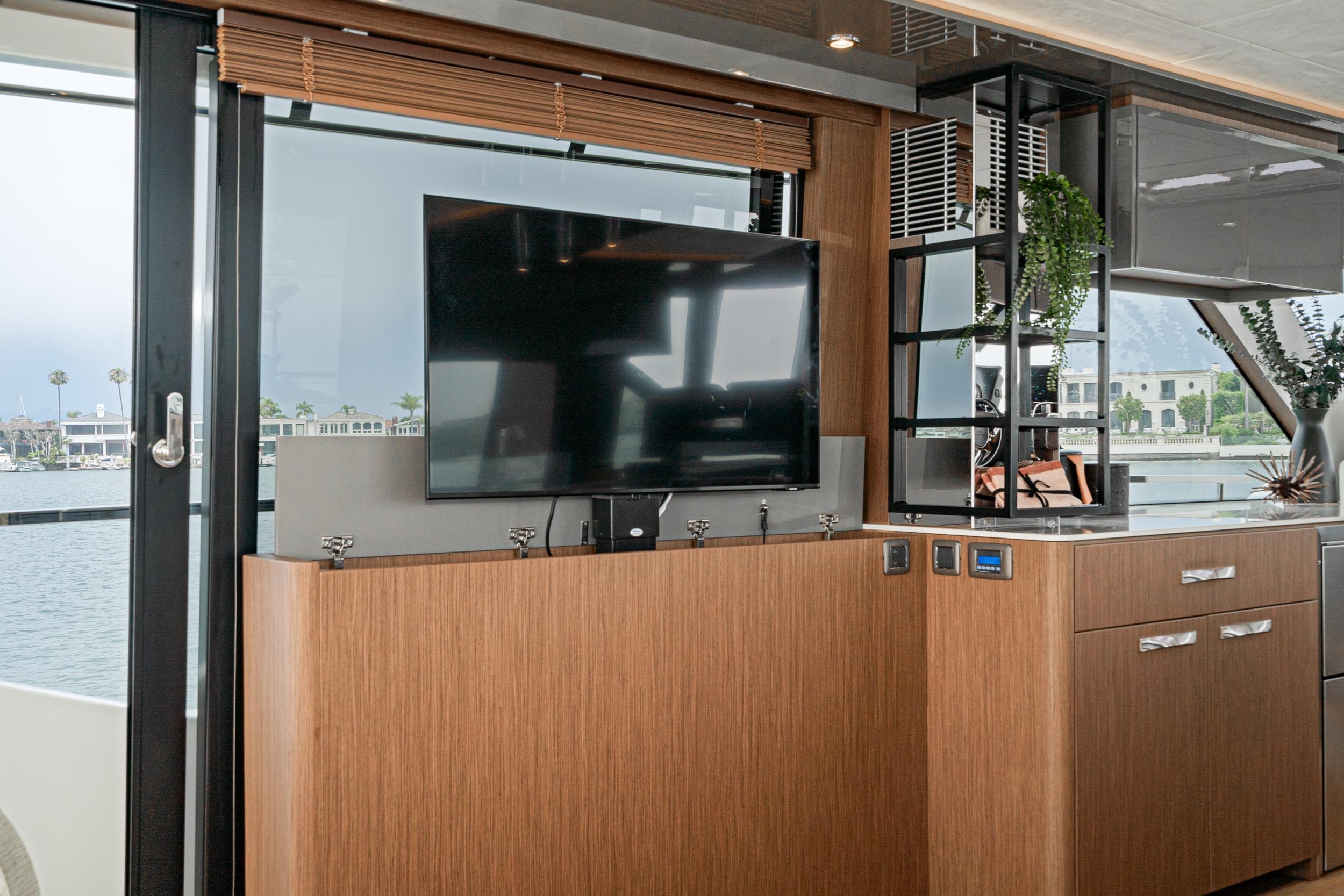 2024 Prestige X60 yacht interior with modern TV setup and elegant wood cabinetry.