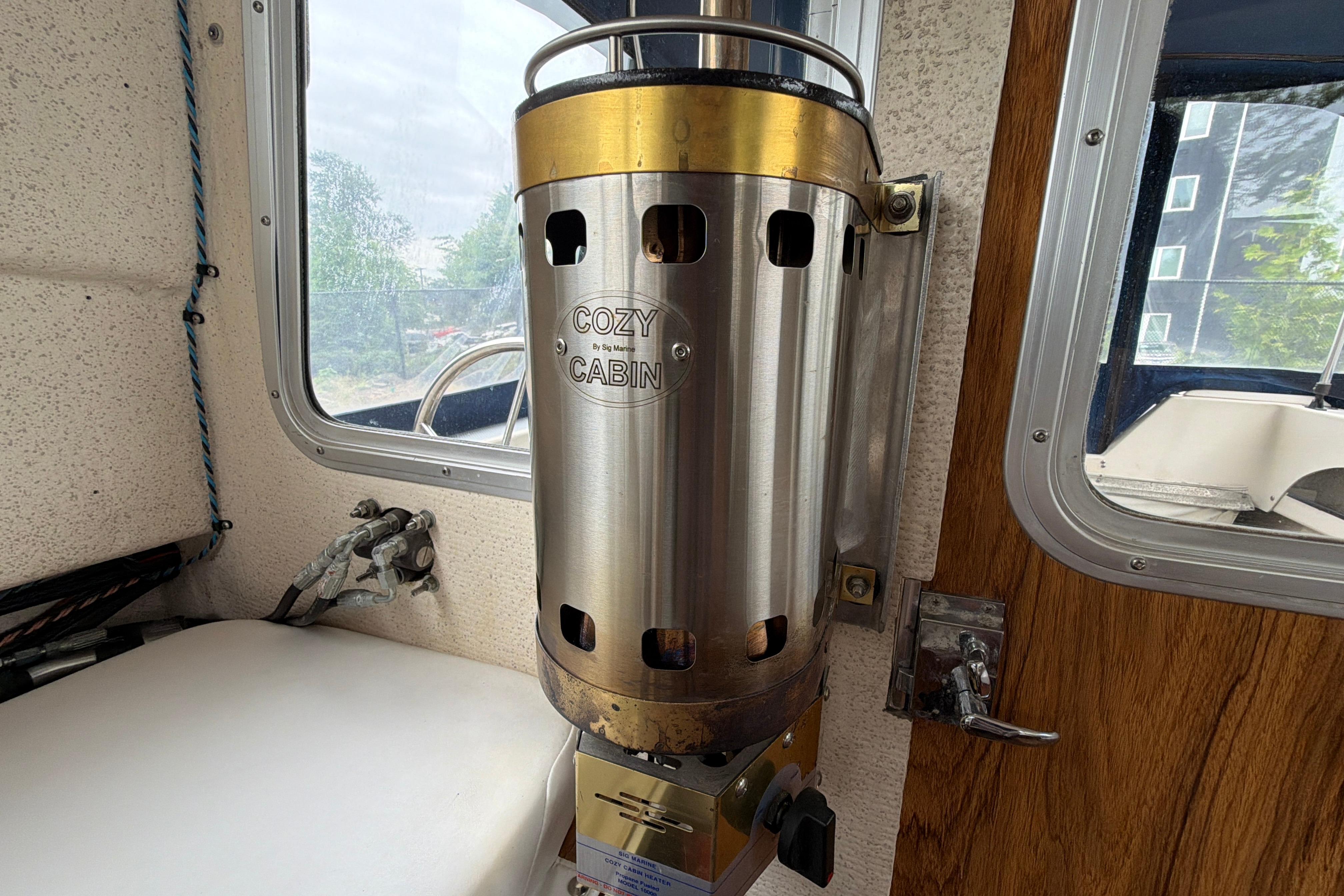 Cozy cabin heater inside 1989 C-Dory 22' Angler boat, near window and wooden door.