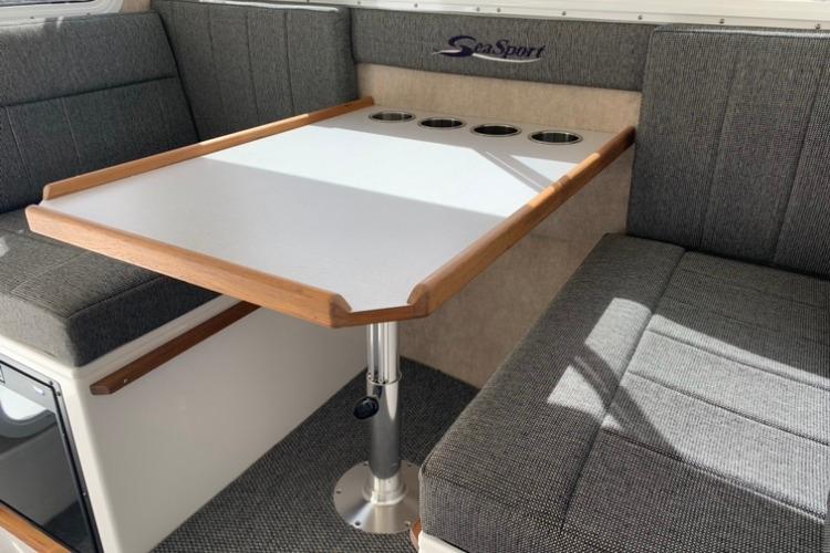 2026 Sea Sport Kenai 2600 interior with gray seating and a wooden-trimmed table.