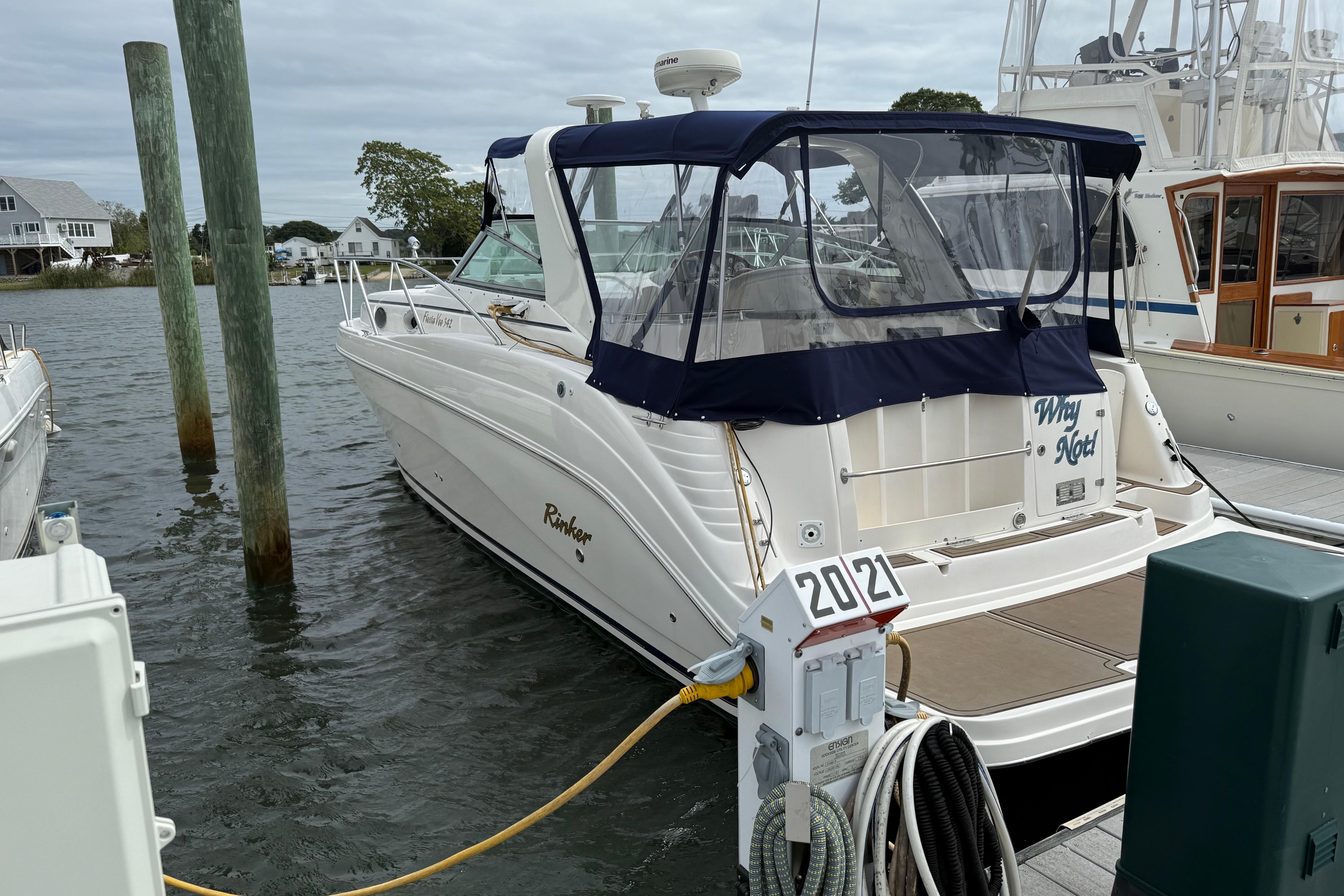 2004 Rinker 342 boat docked at marina with blue canopy and white hull.
