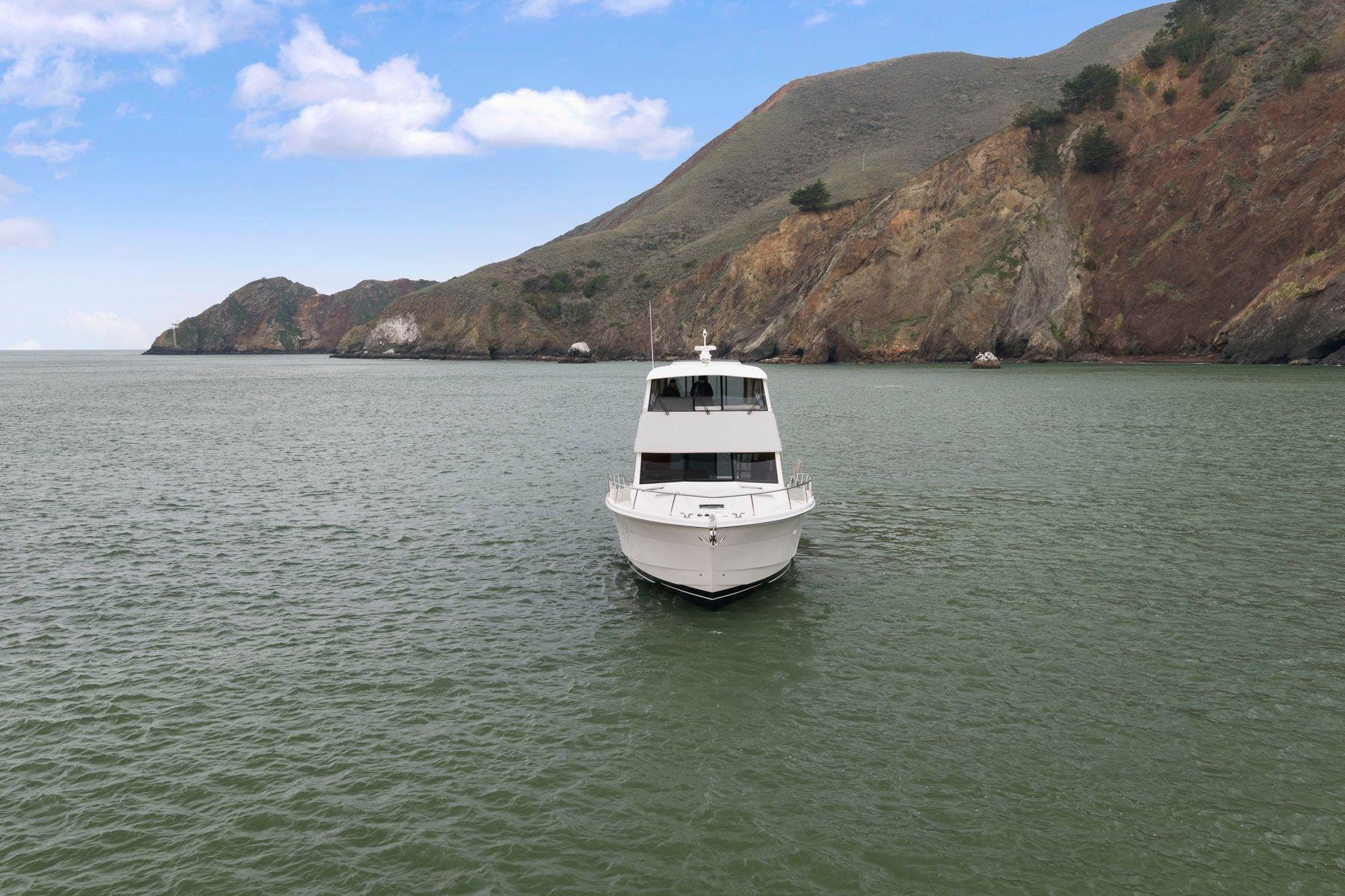 2014 Maritimo M50 yacht on calm waters with scenic rocky coastline.