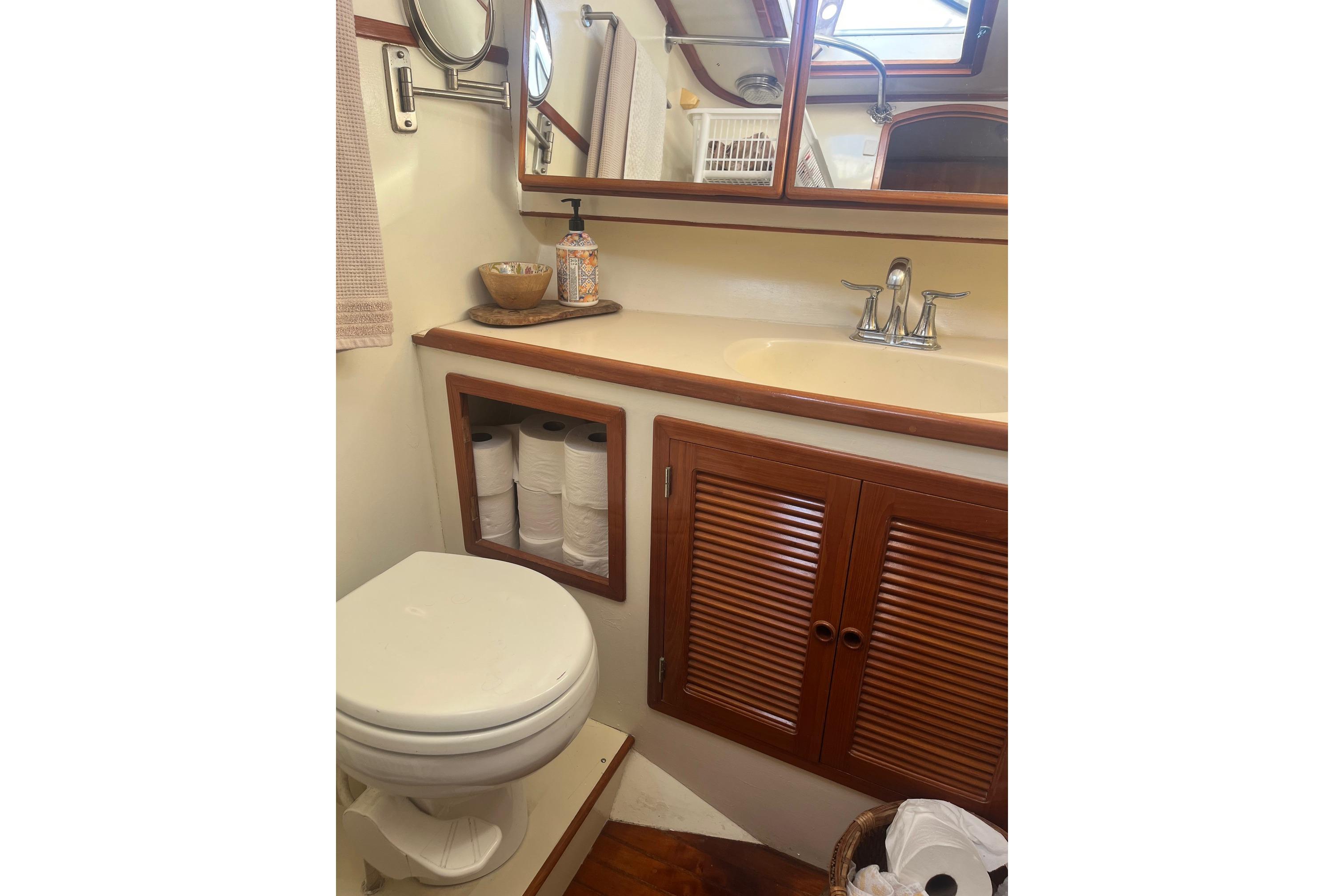 Bathroom interior of 1990 Mikelson 48 Sportfisher yacht with wooden cabinets and sink.