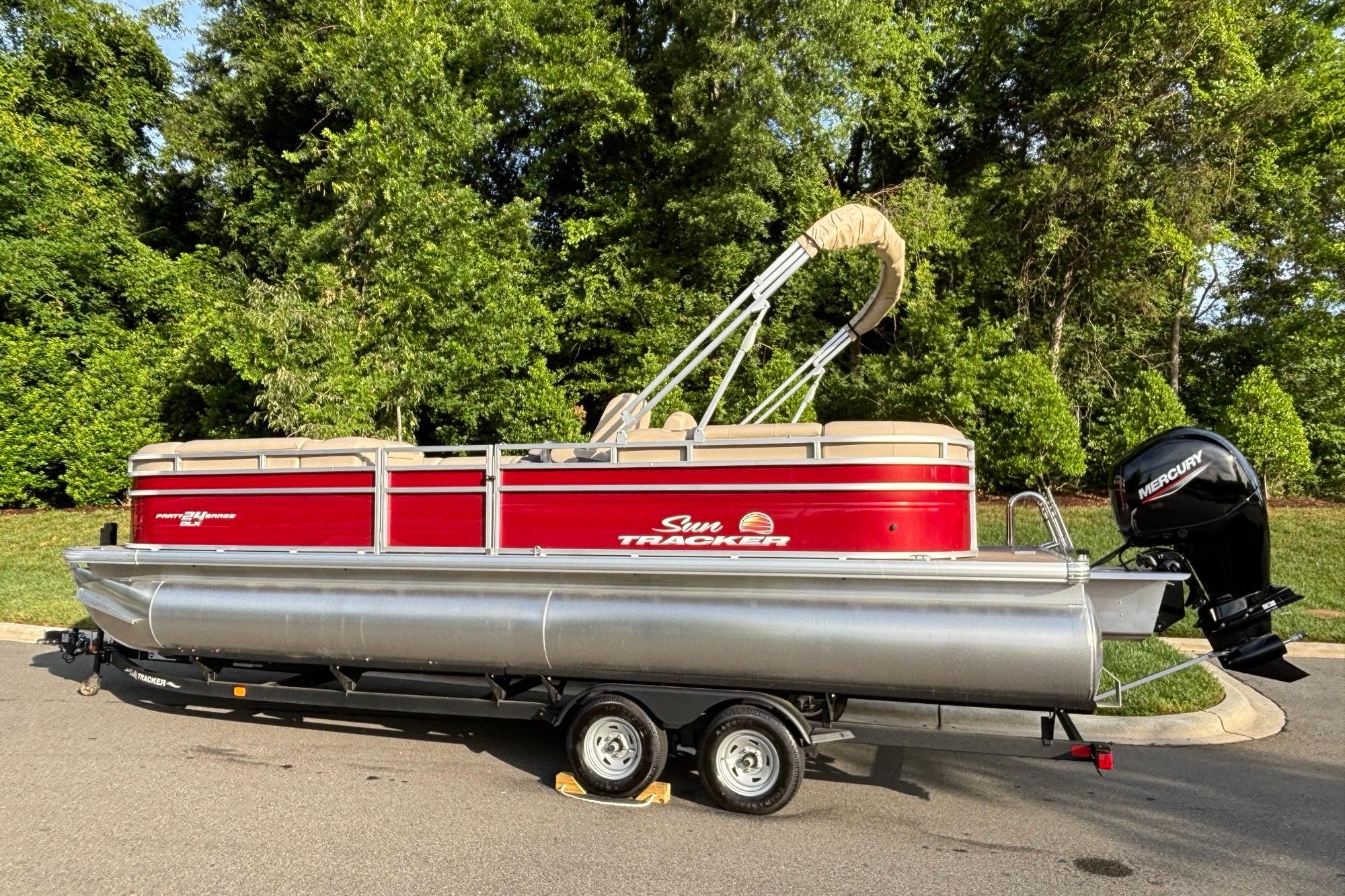 2025 Sun Tracker Party Barge 24 DLX pontoon boat on trailer, parked outdoors.