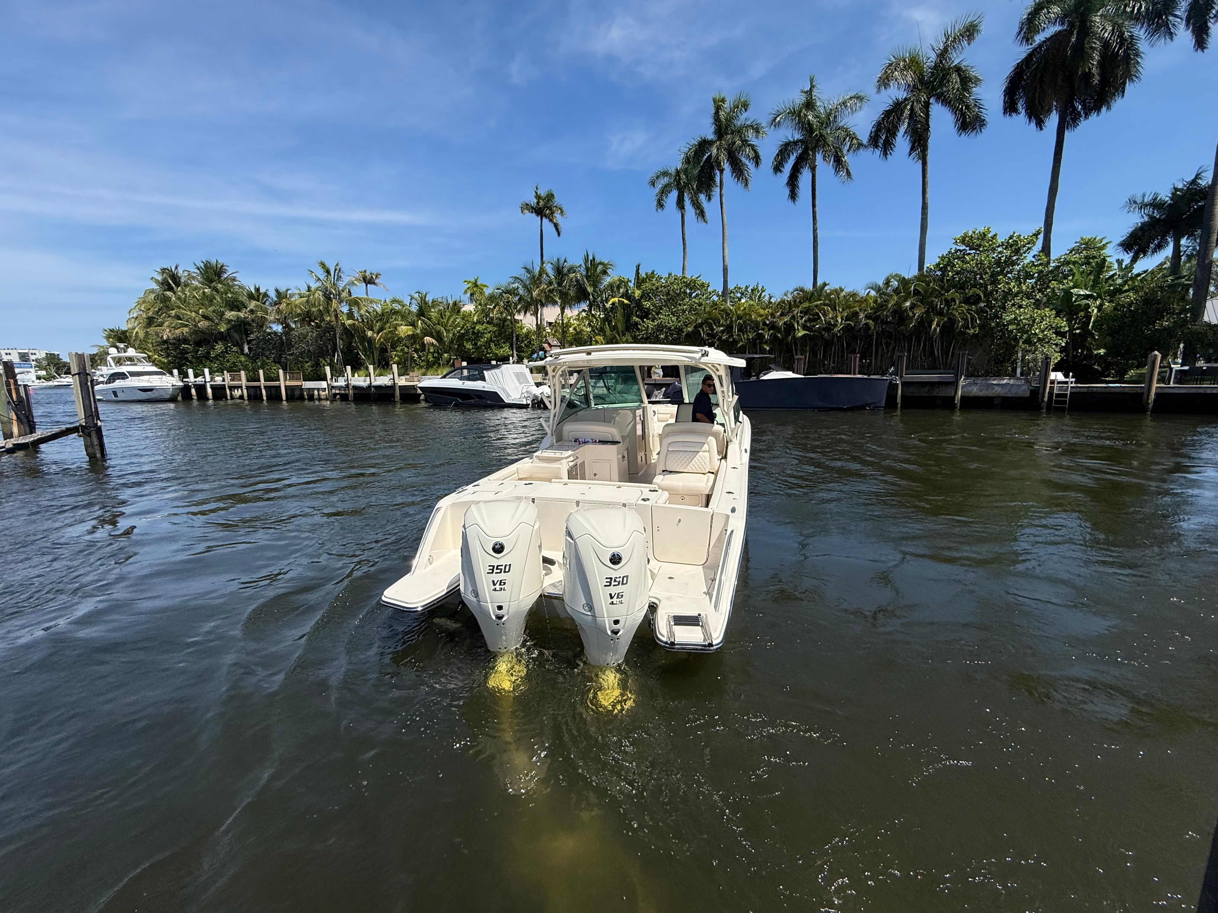 A Grady-White Freedom 325 boat on the water, surrounded by palm trees and other boats.