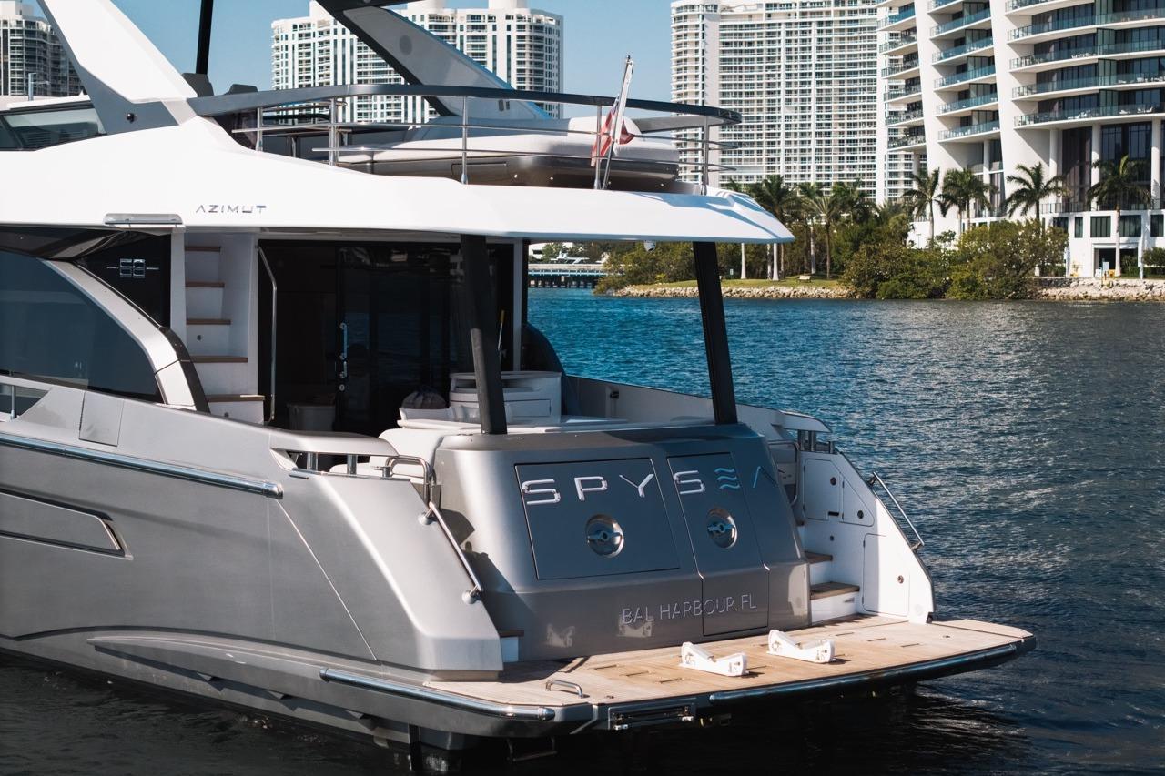 2023 Azimut Fly 68 yacht docked near modern waterfront buildings.