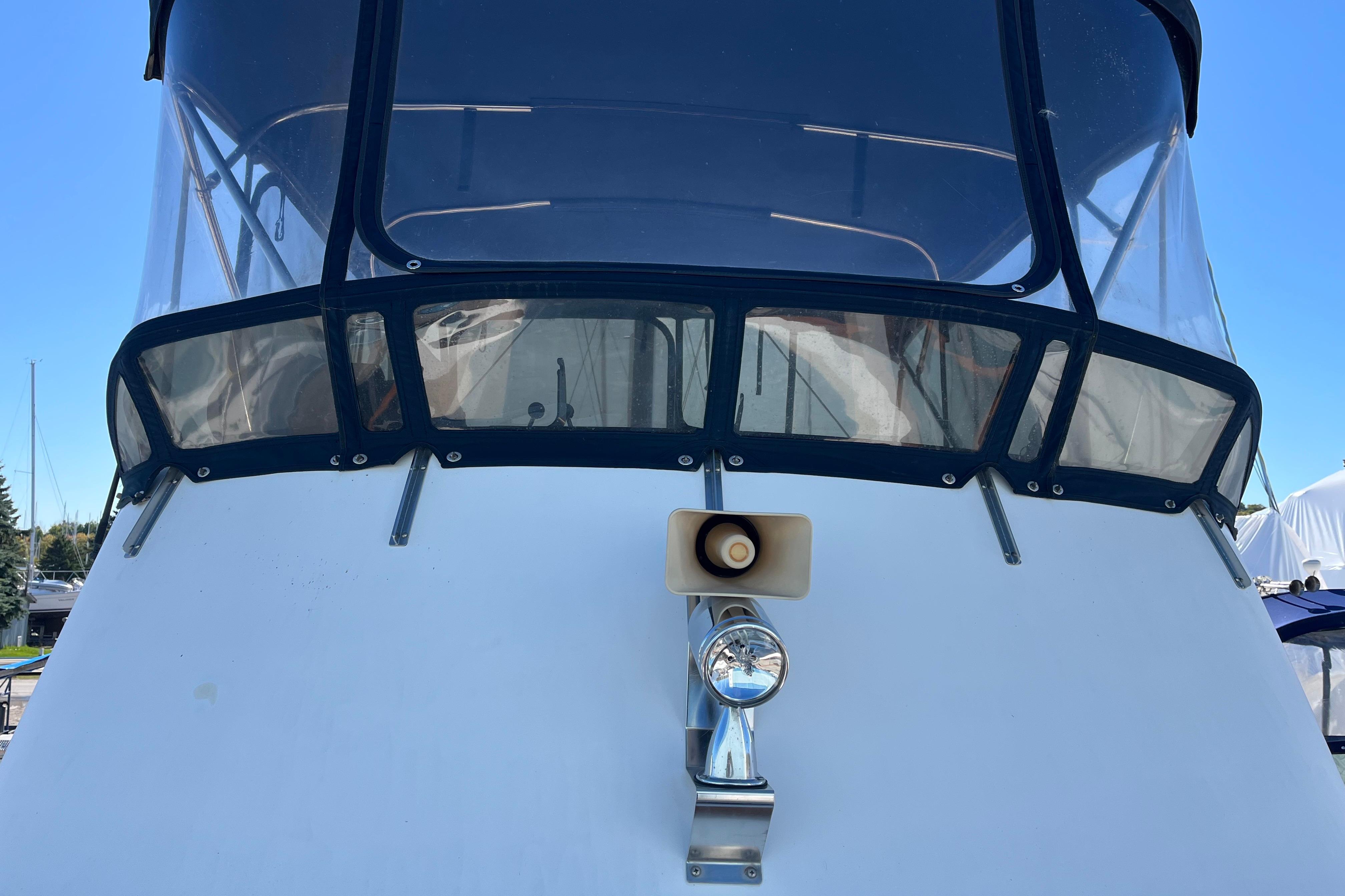1987 Monk 36 boat with enclosed cockpit and spotlight, docked at marina.