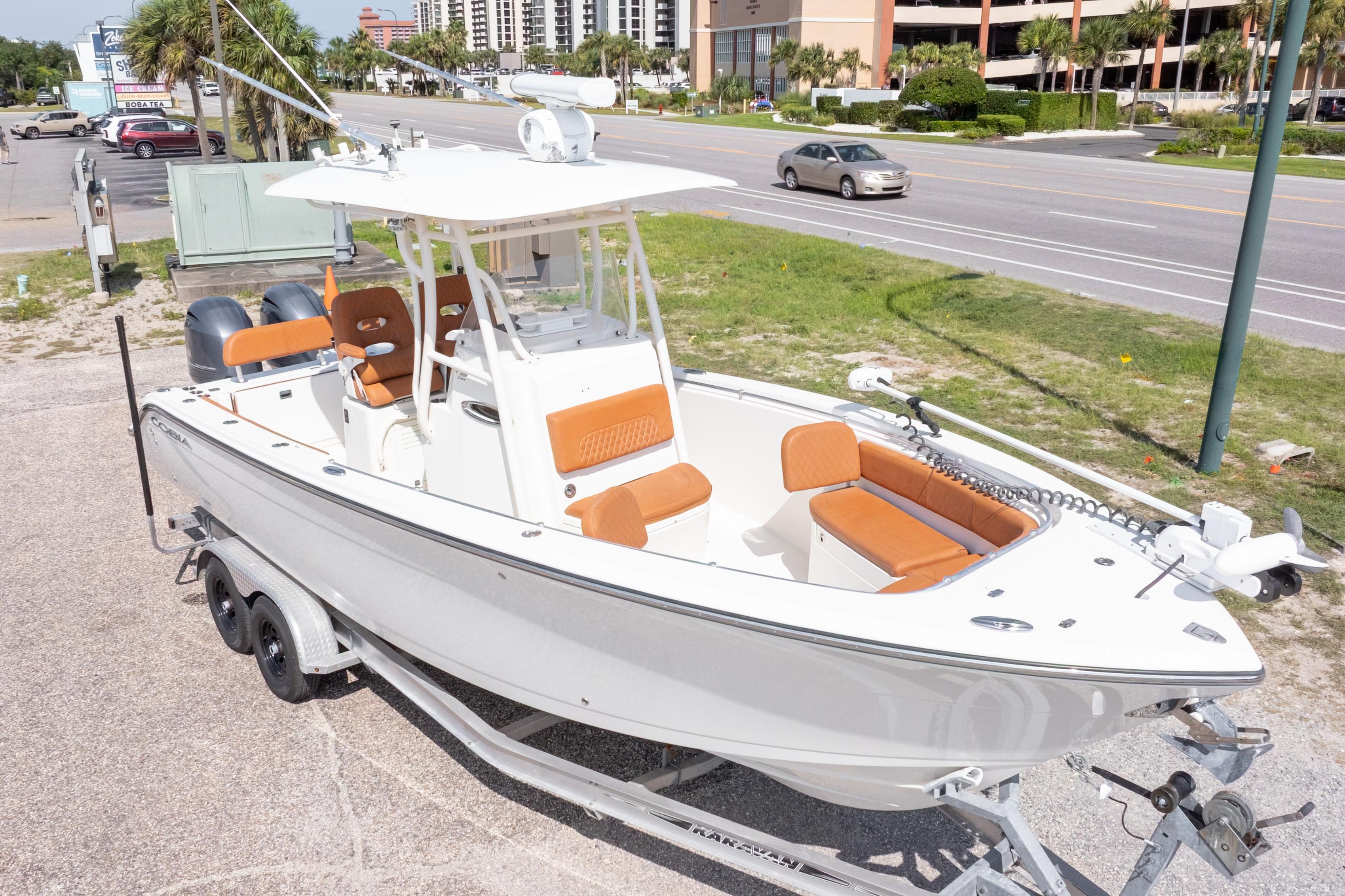 2017 Cobia 261 Center Console boat on trailer, parked near a road with palm trees.
