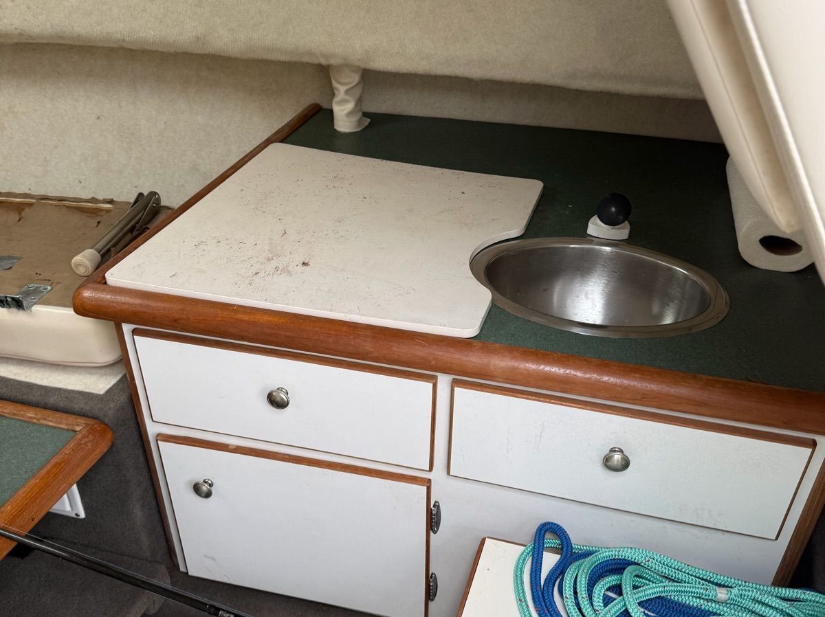 Small kitchenette with sink and cutting board in a boat.
