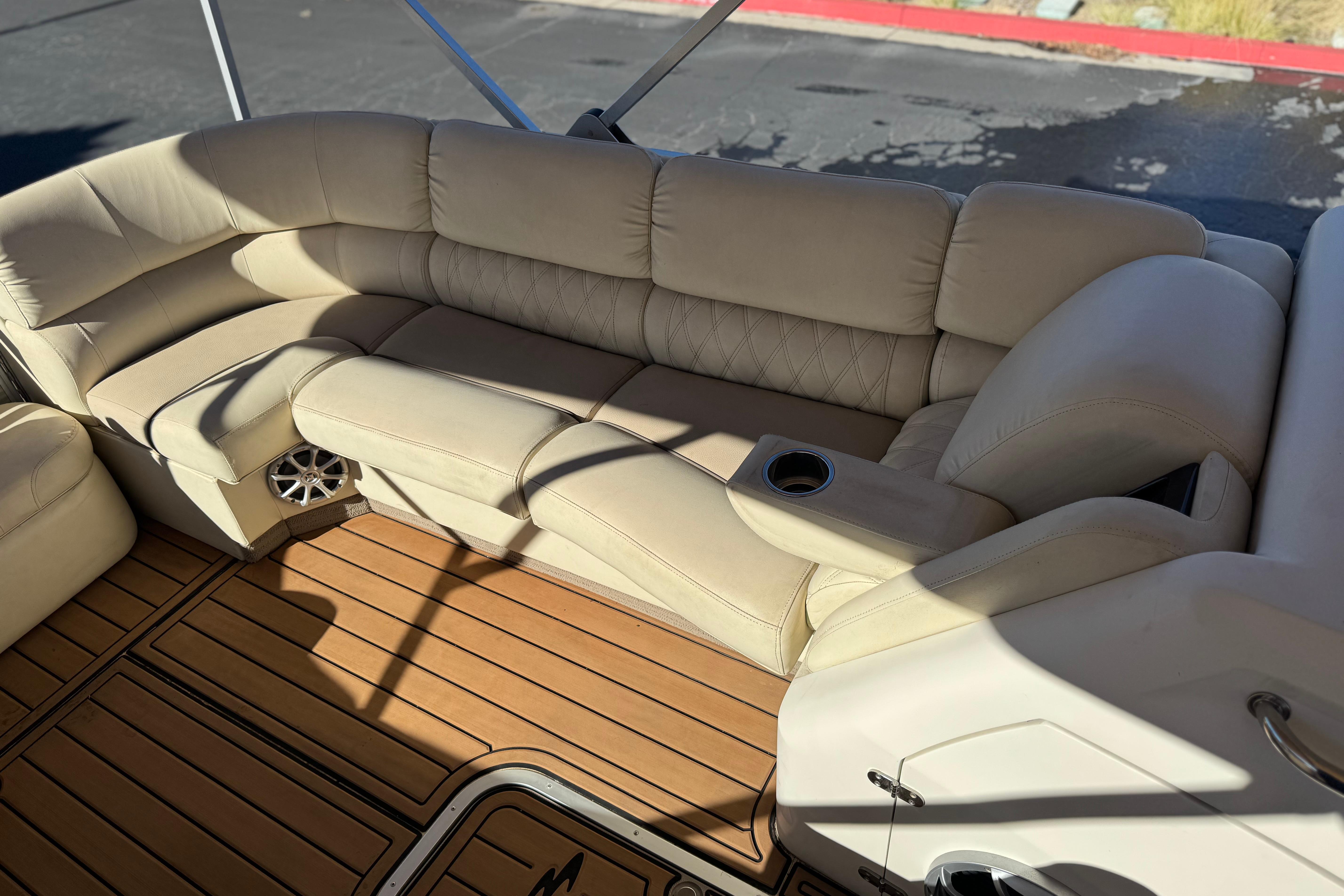Luxurious seating on 2013 Bennington 2575QCW I/O boat with beige upholstery and wood flooring.