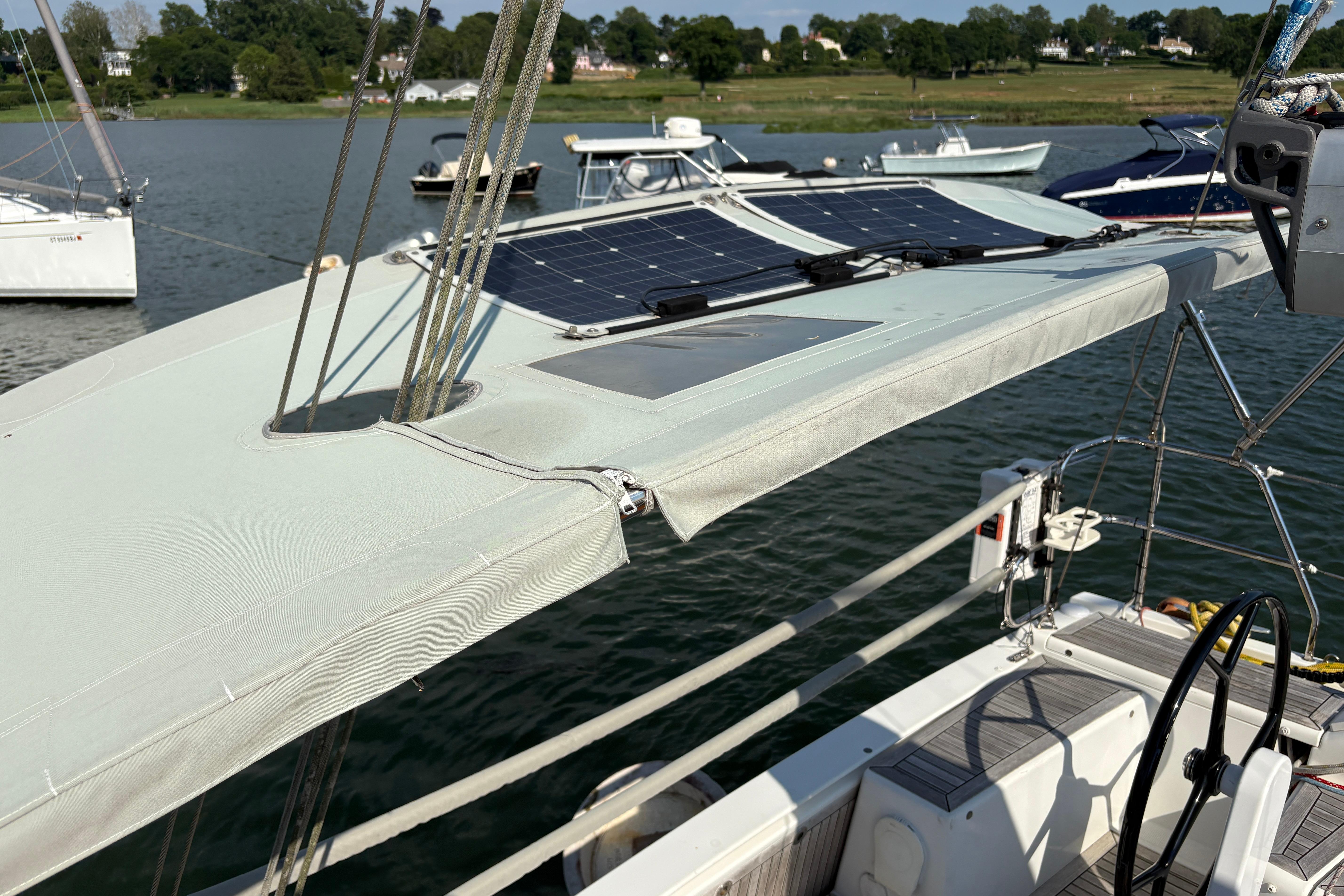 Sailboat Hanse 415 (2014) with solar panels on deck, docked by a scenic shoreline.