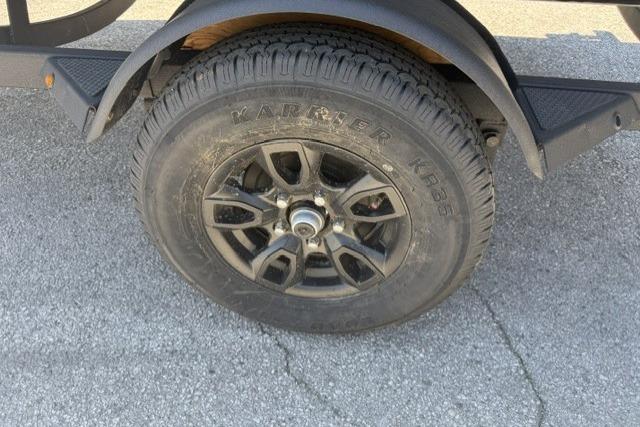 Trailer wheel of 2026 Tracker Pro Guide V-16 SC on asphalt surface.