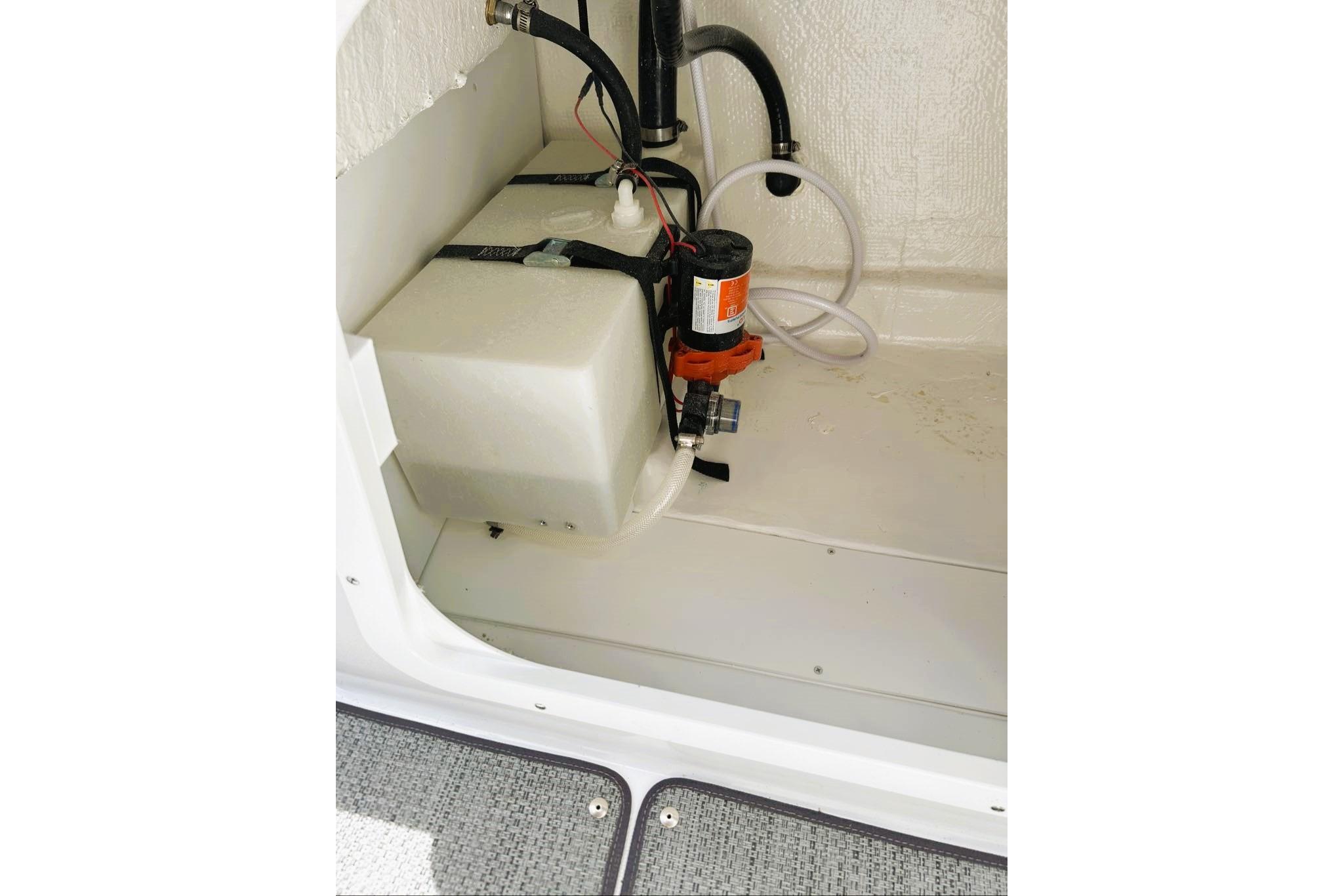 Interior view of 2026 Tahoe 2150 boat's storage compartment with pump and hoses.