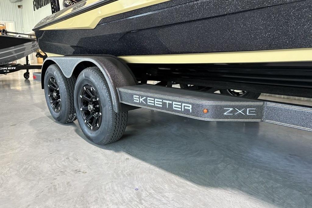 2026 Skeeter ZXE21 boat trailer with dual black wheels in a showroom.