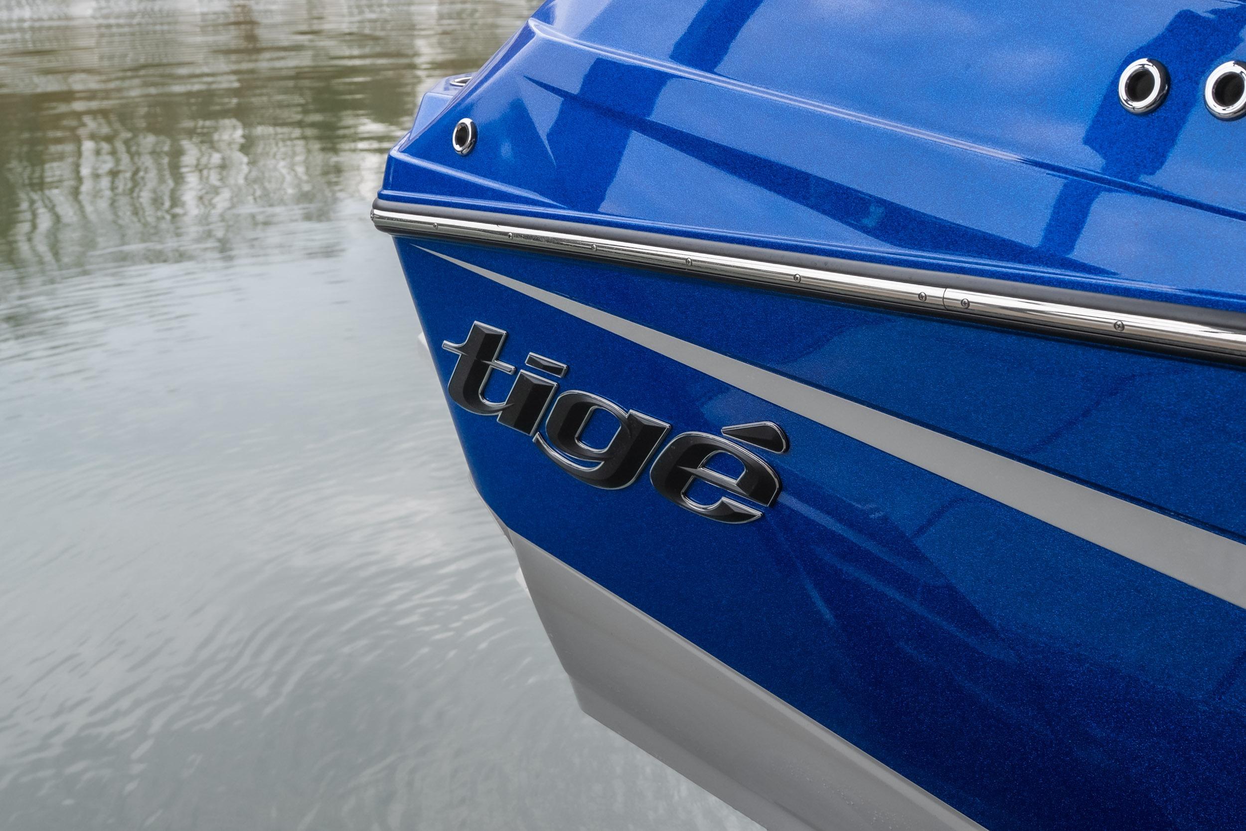 2026 Tigé Z3 boat, blue hull with logo, reflecting on calm water.