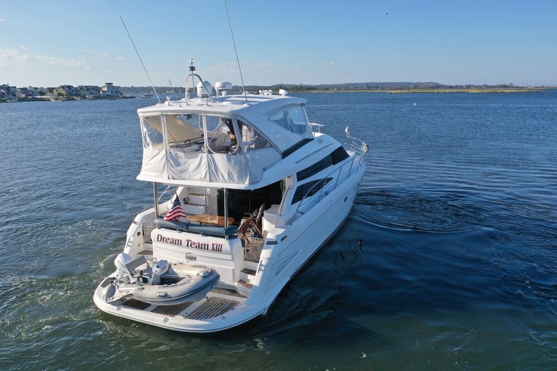 2005 Neptunus 56 Flybridge yacht cruising on a serene waterway.
