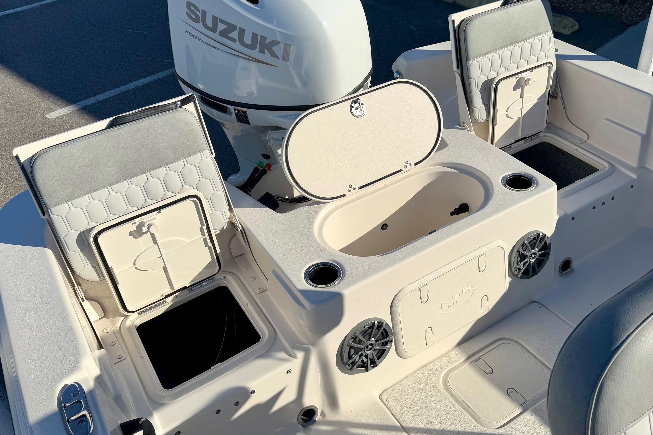 2025 Carolina Skiff 21 LS boat interior with Suzuki engine, storage compartments, and seating.
