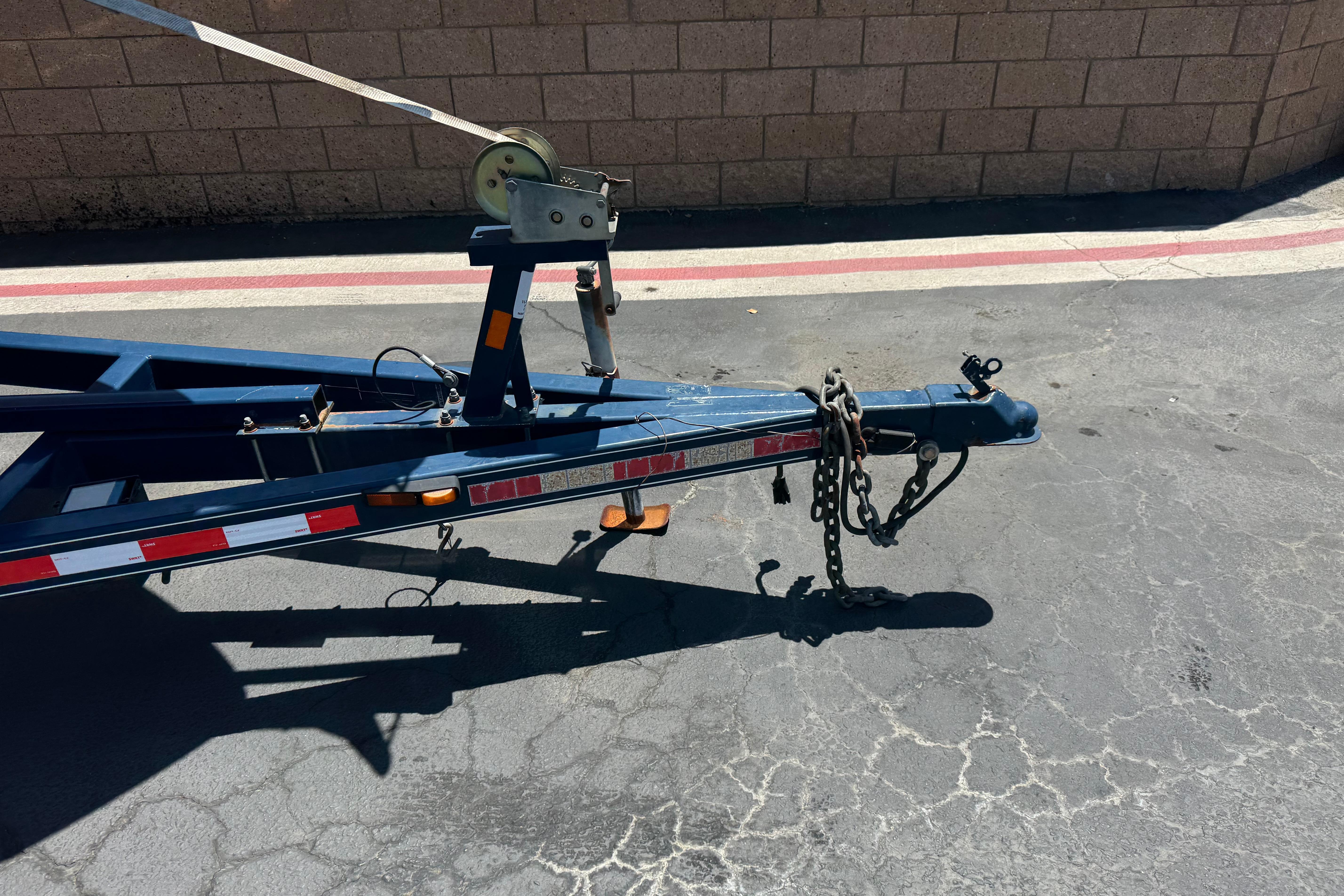 Trailer hitch and winch of a 2013 Regal 28 Express boat trailer on pavement.