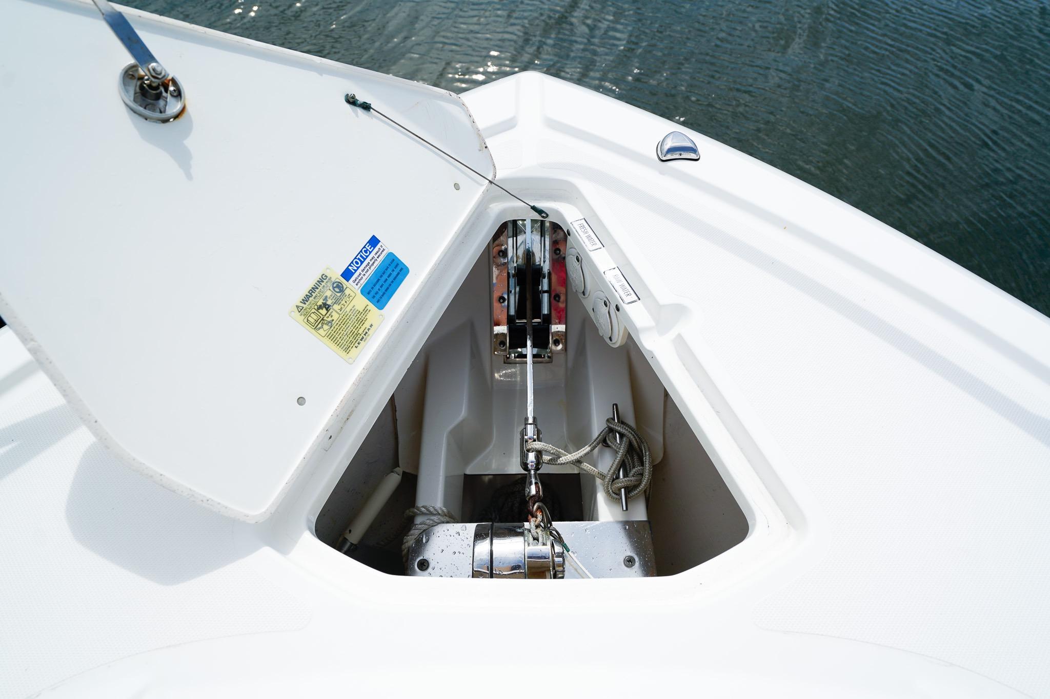 Anchor compartment of 2020 Pursuit OS 325 Offshore boat, open lid, visible ropes and mechanism.